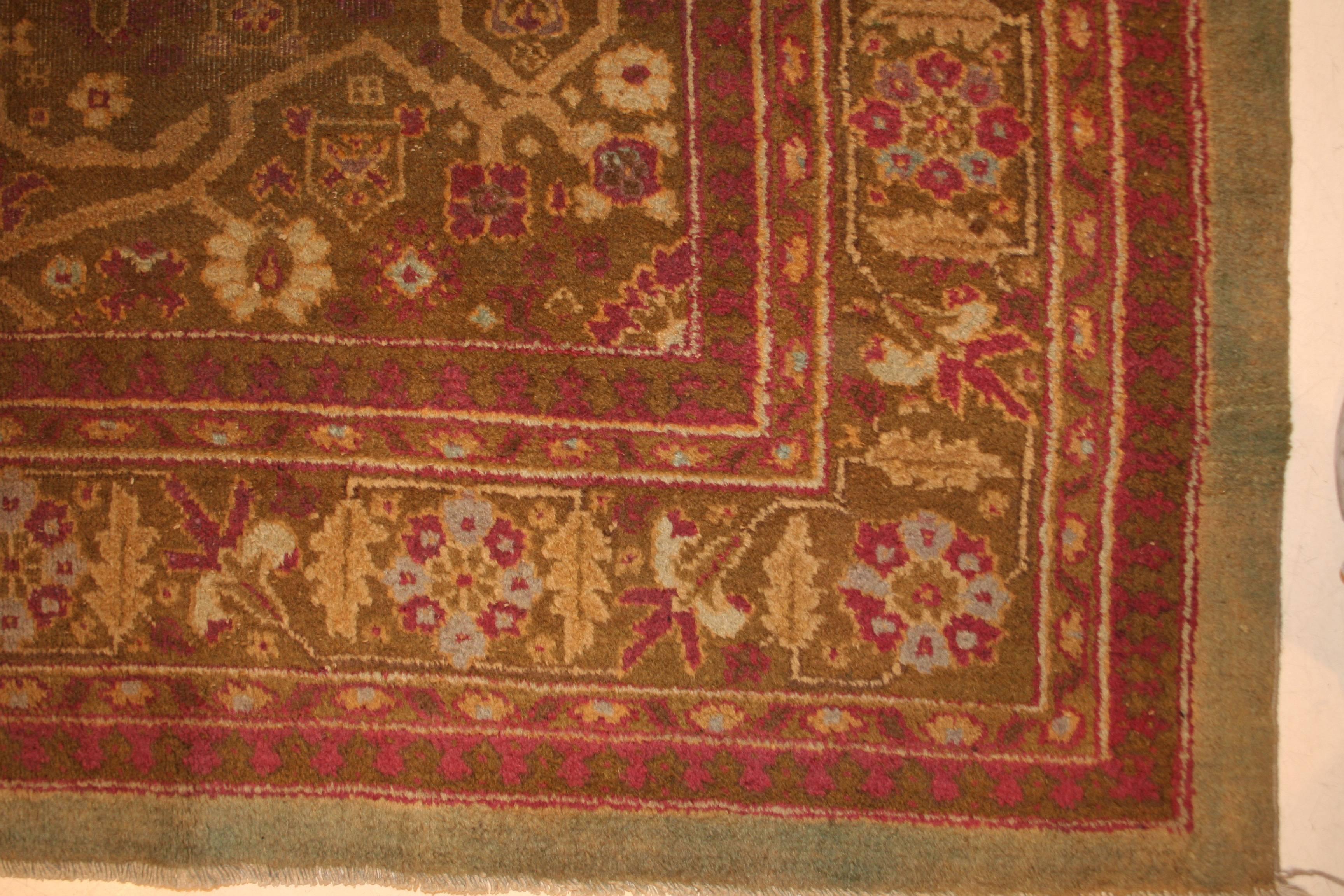 Characterized by a very unusual light green background, this fine Amritsar carpet is distinguished by a small medallion with pendants layered onto a large cartouche acting and an open field. This cartouche is placed over an aubergine background