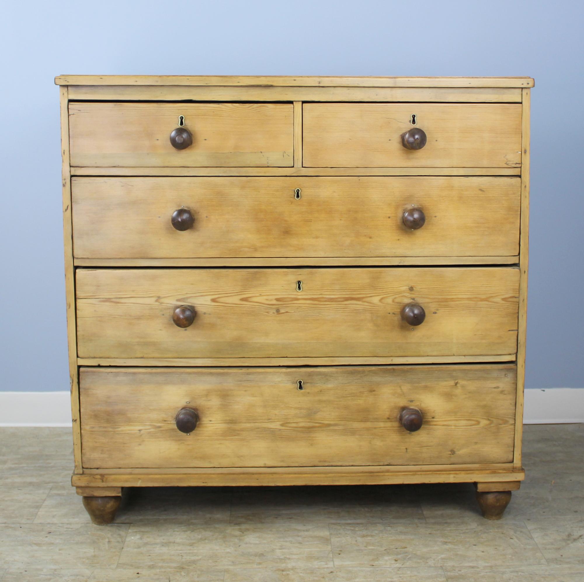 A classic early English pine chest of drawers, two over three construction. The wood has been scrubbed back and enriched with a dark wax polish to bring out the grain and natural pine color. Drawers run smoothly and have simple round knobs for a