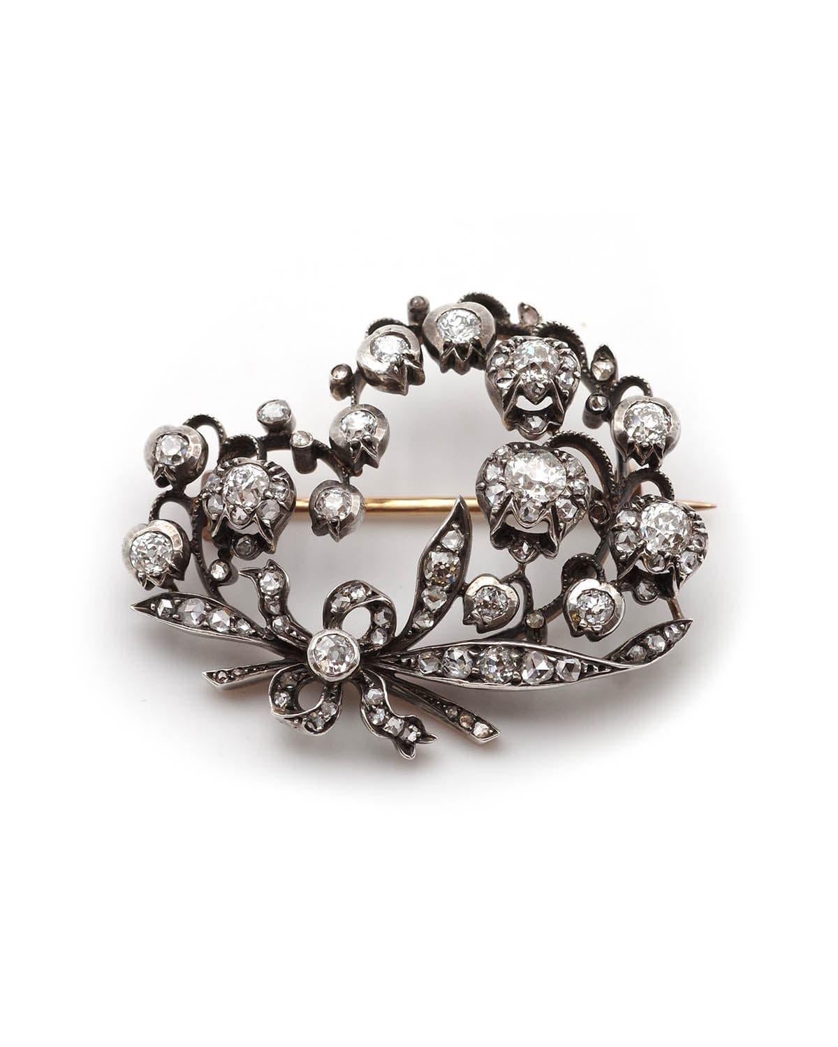 Broche Lily Antiques en or 18 carats et argent, ornée de diamants. Grande broche présentant deux brins de muguet recourbés vers l'intérieur, retenus par un nœud. La broche est entièrement sertie de diamants de taille ancienne, totalisant environ 3