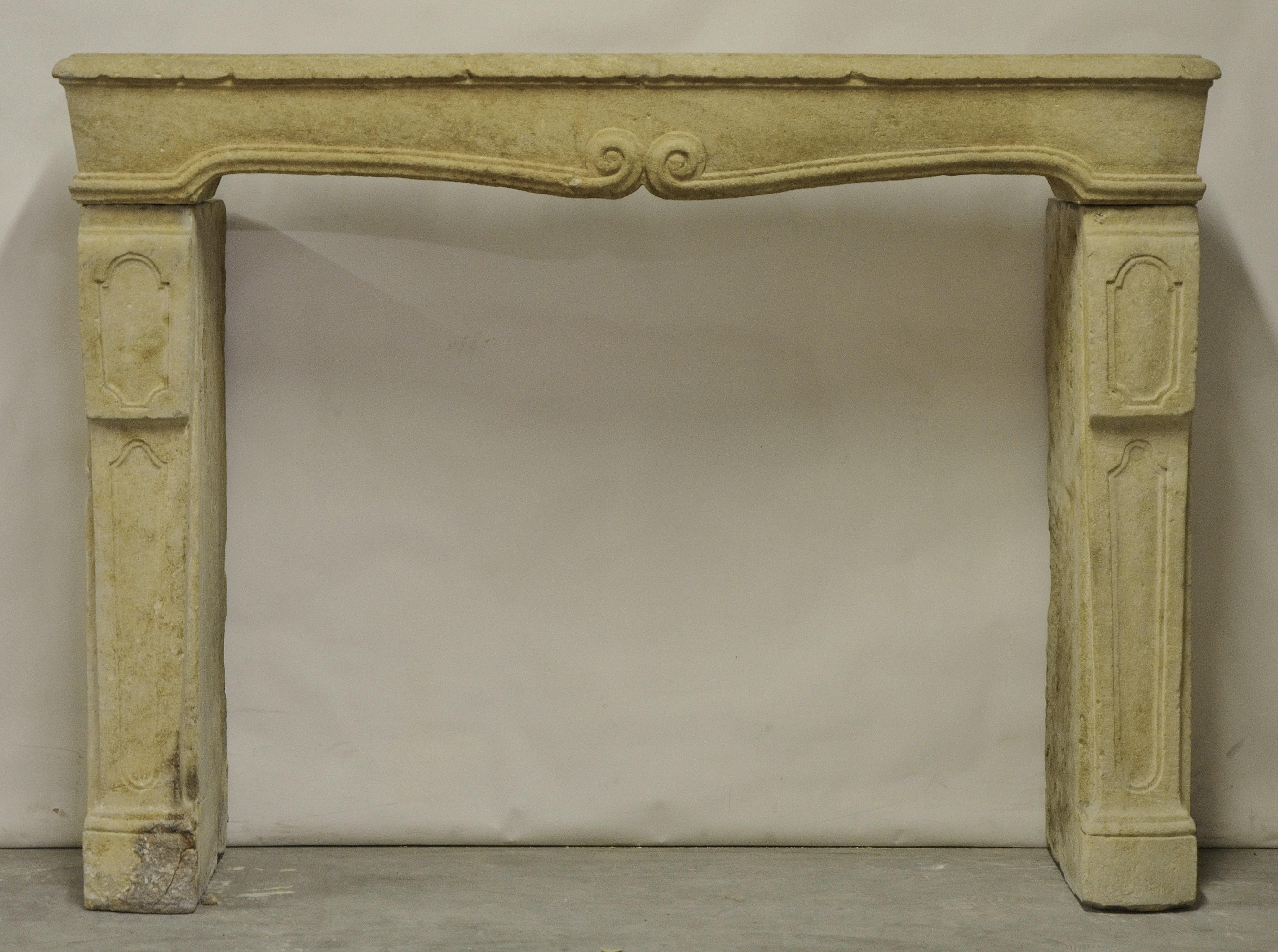 A robust tall and elegant French limestone fireplace mantel in Louis XIV style.

The mantel is made from three solid pieces, the frieze has a nice shaped and profiled top with two centered stylish curls. The jambs are decorated with panels and are