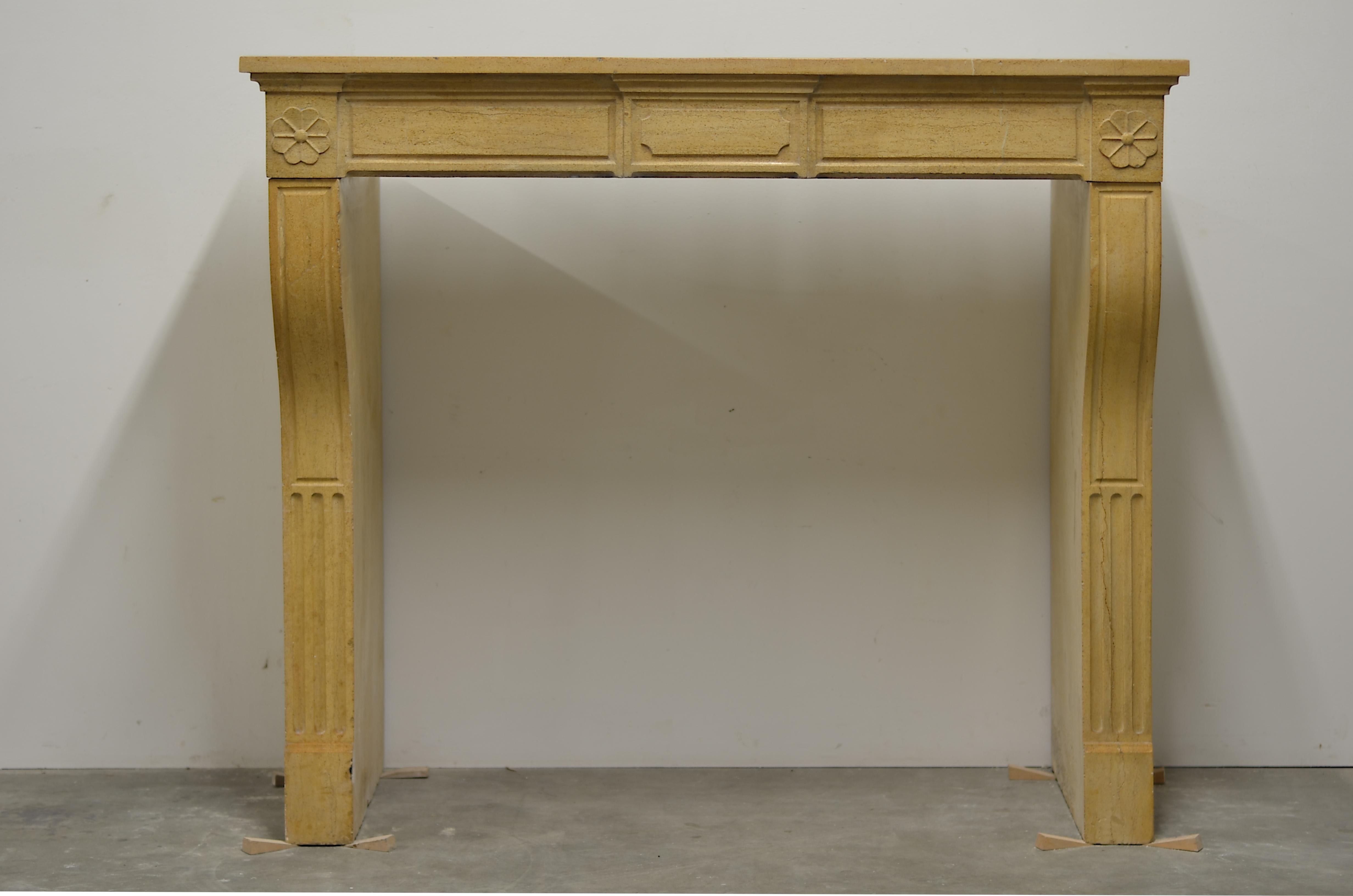 19th century French Louis XVI style fireplace mantel in nice warm limestone.
This nice and clean looking paneled Louis XVI is adorned with two lovely stylish flowers on both sides of the frieze.

It is in great overall condition, lovely