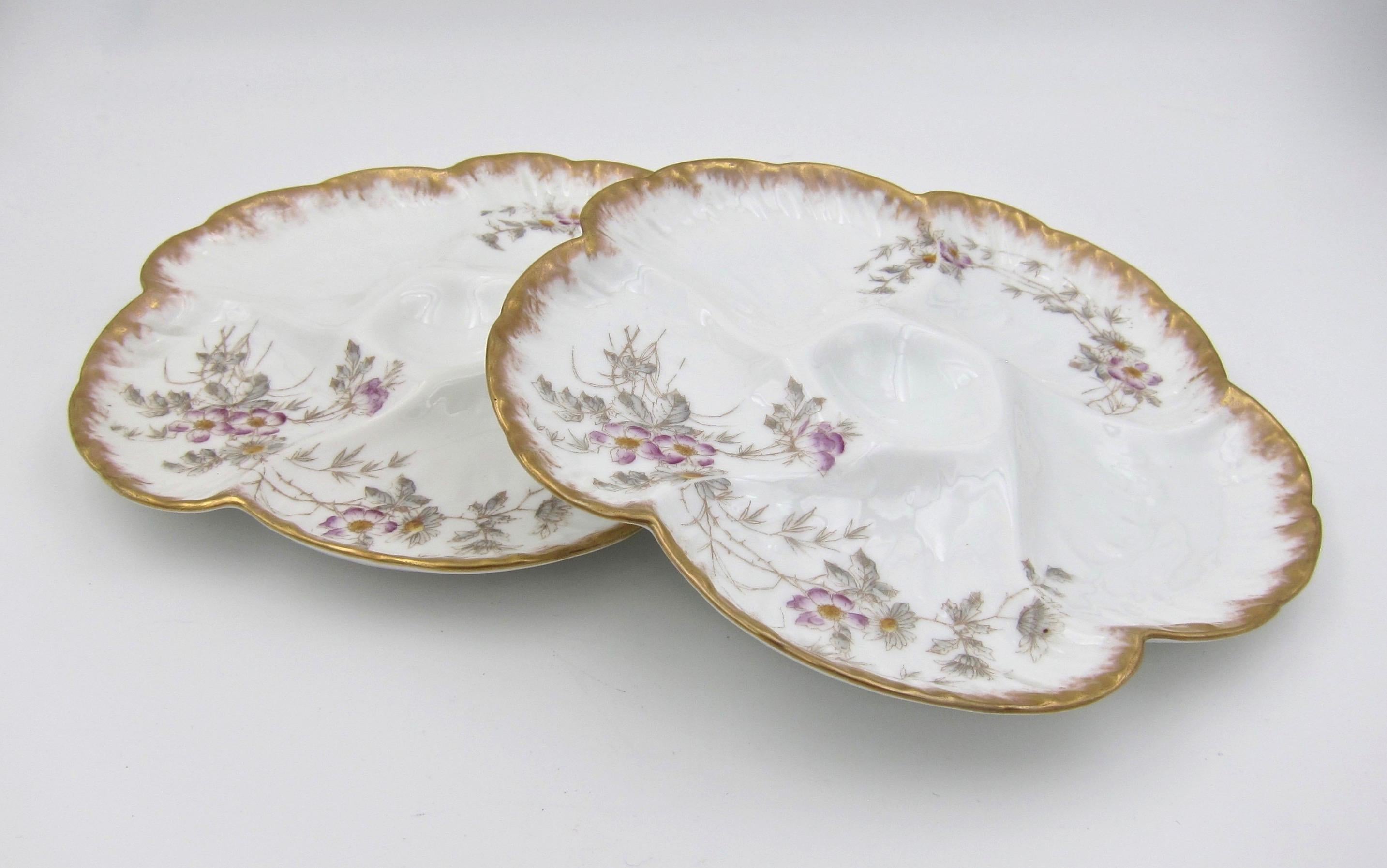 A French pair of antique porcelain oyster plates from Société Gérard, Dufraisseix and Morel (formerly Charles Field Haviland) of Limoges, France. The molded 'Wave' pattern design includes five wells for oysters over ice surrounding a smaller,