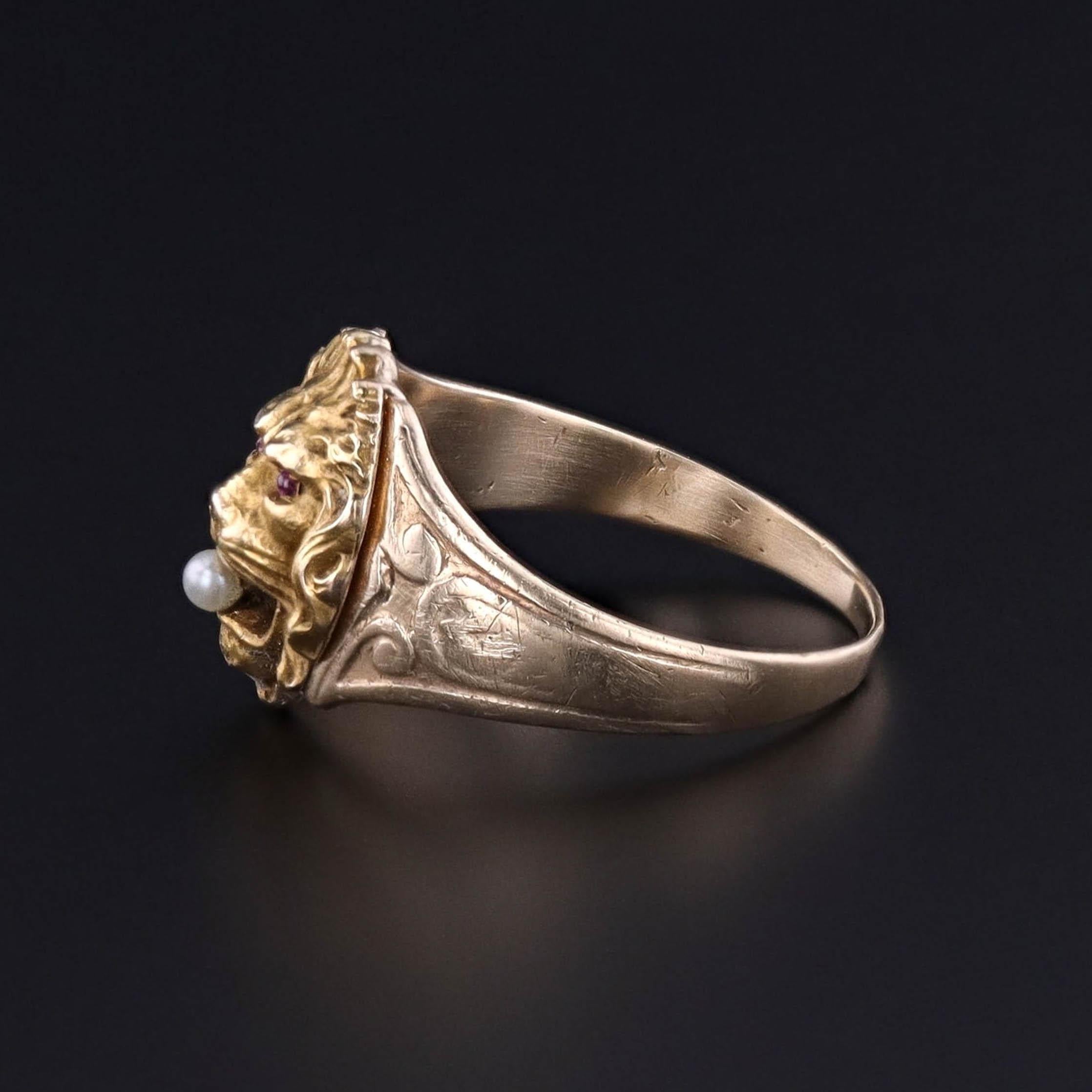 Antique Lion Ring: This ring features a 14k gold lion's head with ruby eyes and a pearl in its mouth. It was created by welding an antique stickpin head (circa 1890) onto an antique, 10k gold signet ring (circa 1910).

The face of the ring measures