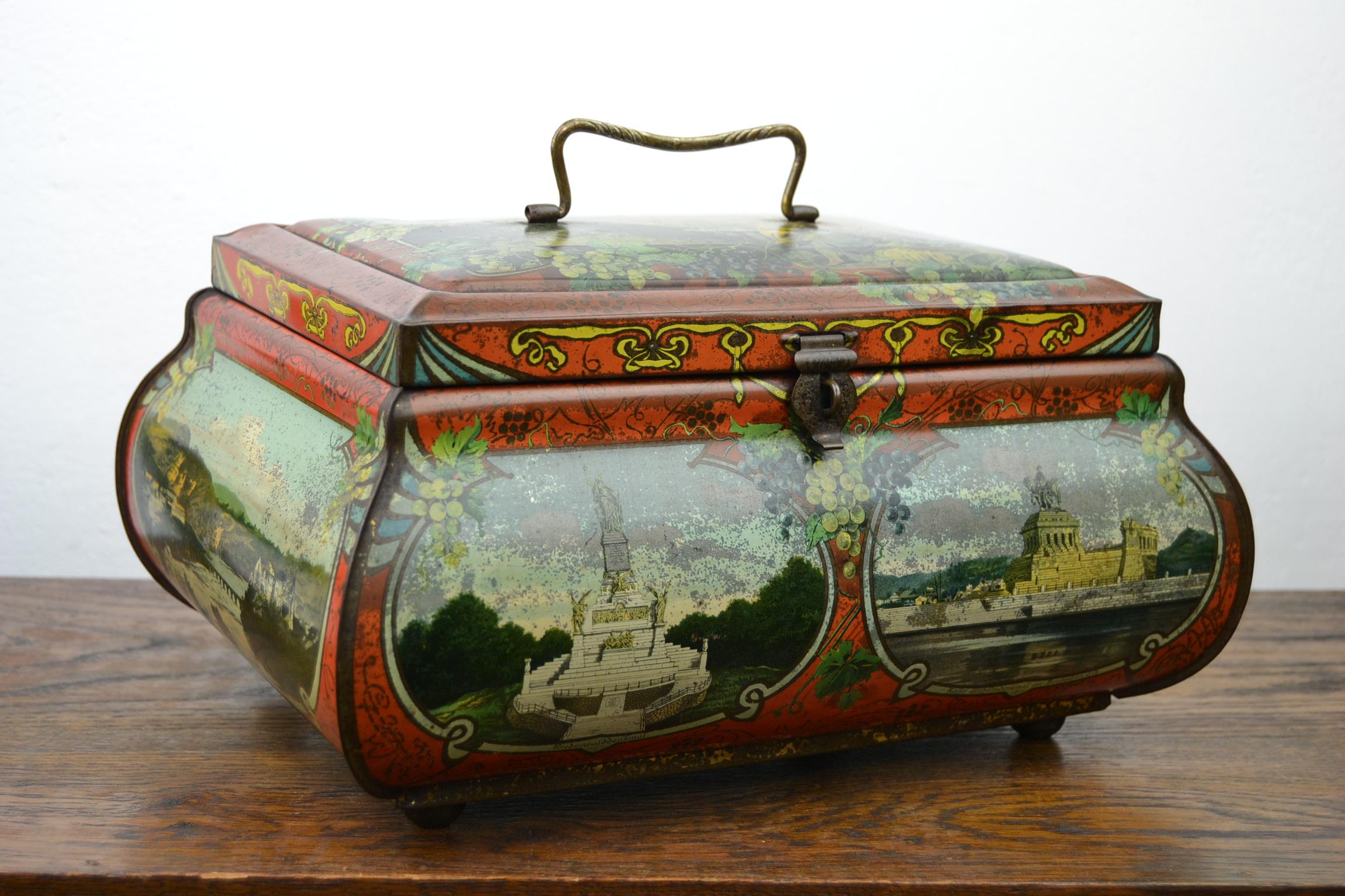 Beautiful lithographic tin with lid, handle and lock.
This tin storage box has a nice shape, beautiful colors and Graceful Art Nouveau Patterns.
It has German places all around, they are located between Koln - Cologne and Zurich. 

On top of the