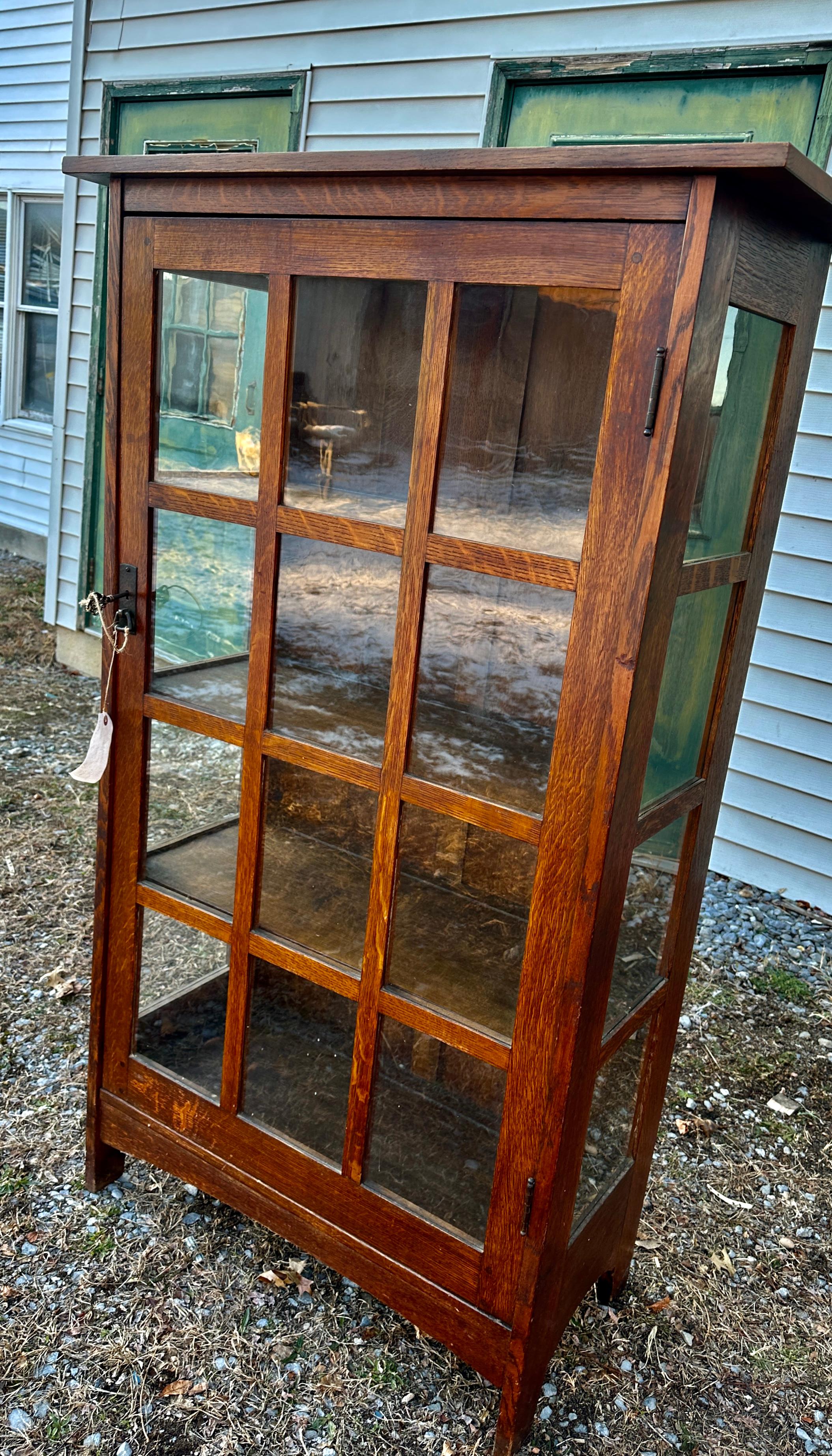 This is an antique L&JG Stickley 1-Door China Cabinet in excellent condition. It has the original finish in excellent condition and original hardware with minimal loss of patina.  The door has 12 individual panes of glass, all original. This cabinet