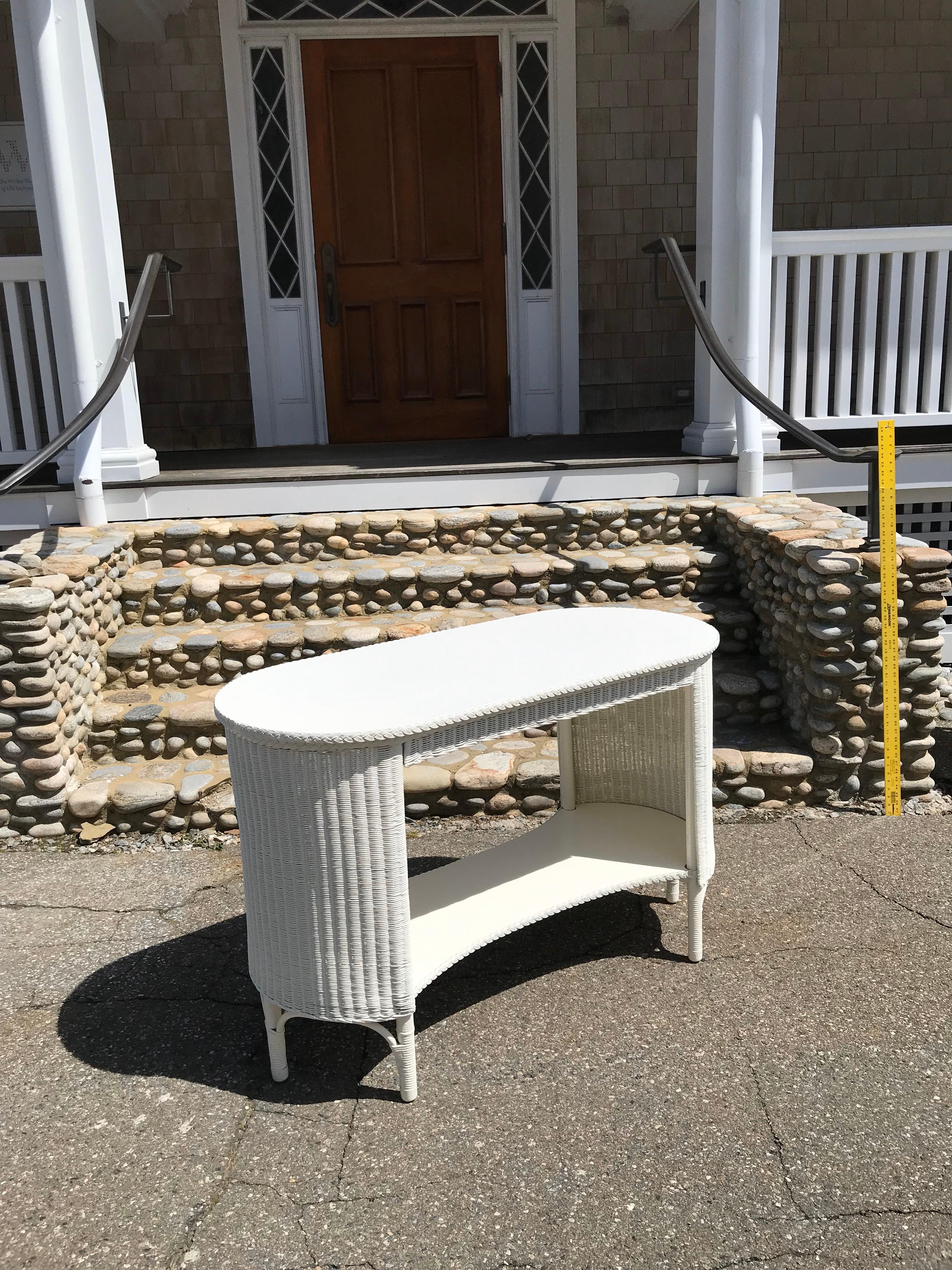 Antique Lloyd Loom table in fresh white paint. Table measures 39” wide, 18” deep and 30” inches tall.