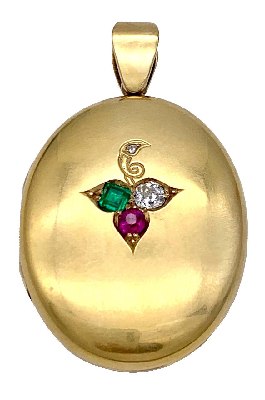 Dieses klobige Belle Époque Medaillon ist mit einem eingravierten Kleeblatt verziert, das mit einem Smaragd im Quadratschliff, einem Diamanten im Rundschliff und einem Rubin im Sechseckschliff besetzt ist. Auf der Rückseite des Medaillons sind die