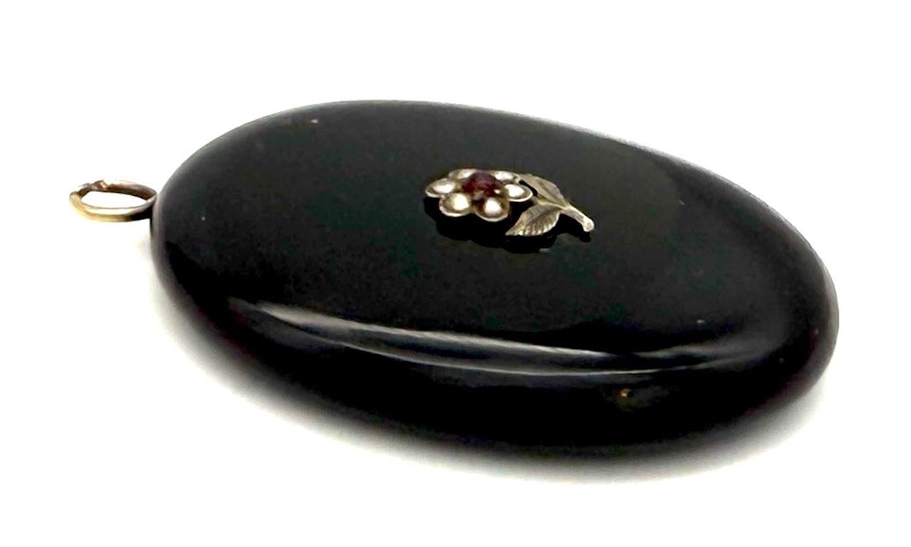Dieser Anhänger wurde um 1850 aus Onyx und Silber gefertigt. Das Zentrum der
 Der Anhänger ist mit einem kleinen Stiefmütterchen aus Naturperlen verziert. Stiefmütterchen heißt auf Französisch pensée, was so viel wie Gedanke bedeutet. Also, in