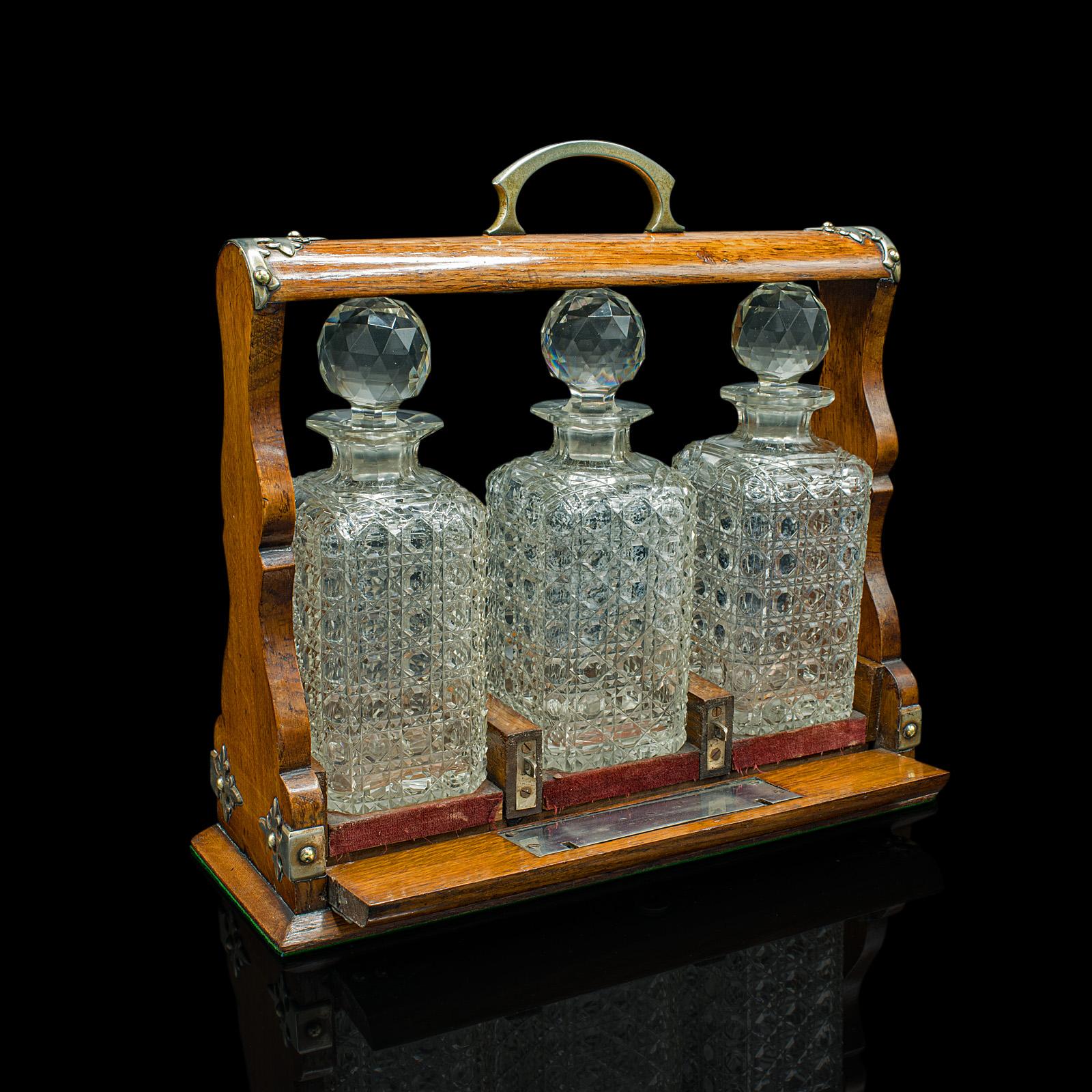 This is an antique locking tantalus. An English, oak and cut glass decanter case, dating to the Edwardian period, circa 1910.

Useful and attractive tantalus with decorative appeal.
Displays a desirable aged patina throughout.
Oak case shows