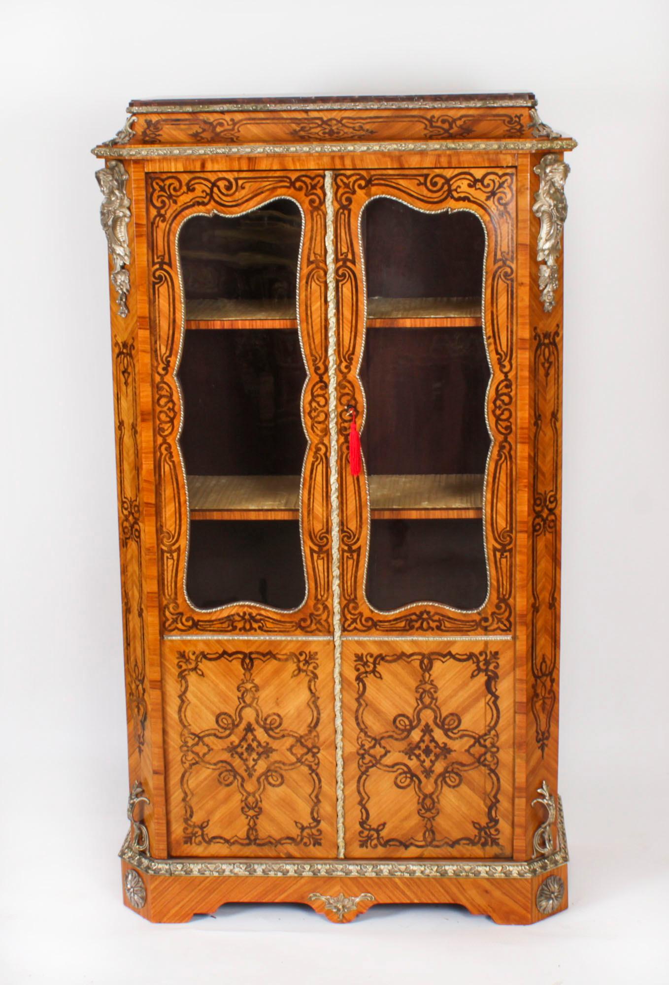 Si tratta di una bella vetrinetta antica in legno e intarsio di Gonçalo Alves, in stile Luigi XV, datata circa 1860. 

La vetrina presenta pannelli decorativi in intarsio floreale ed è sormontata da un piano in marmo Rouge de Rance. La vetrinetta
