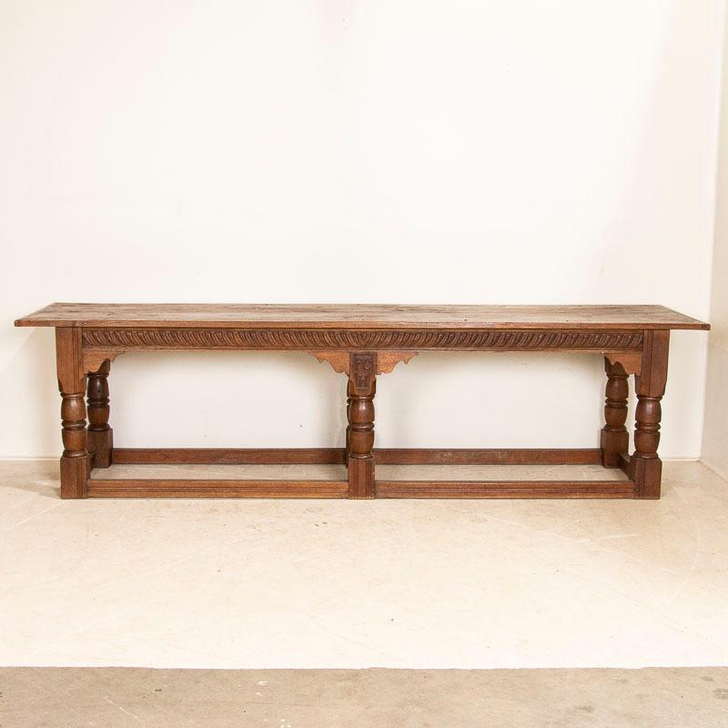 Impressive in size at over 9' long, this French oak library or refectory table is visually stunning with its heavy turned Baroque legs and 4 supportive stretchers. Notice the monogram of PCH carved into the center. Two long planks comprise the top,