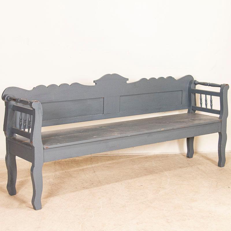 This wonderful country bench has a scalloped back accented by curved arms and legs, adding a slight romantic touch to it. The gray paint was added at some point later in time (you can see the texture of crackled older finish below), which allows it
