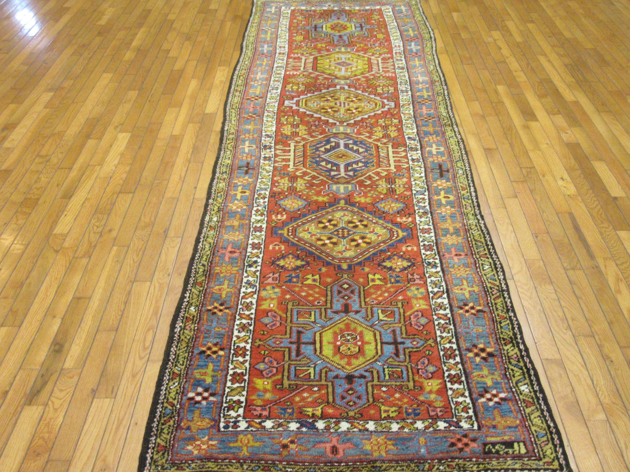 This is an antique hand knotted long Persian Heriz runner rug. It has the trademark multiple geometric medallions design of the neighbouring Karajeh rugs. It is made with naturally dyed wool pile on a cotton foundation. The rug measures 3' 5'' x 11'