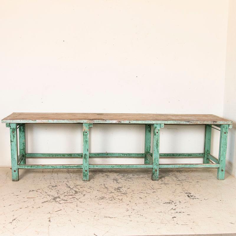 What an amazing find! At over 9 1/2 feet long, this old work table has tremendous appeal thanks to the original green painted base and the stretchers supported by iron rods which give it an industrial edge. The entire table has been restored and