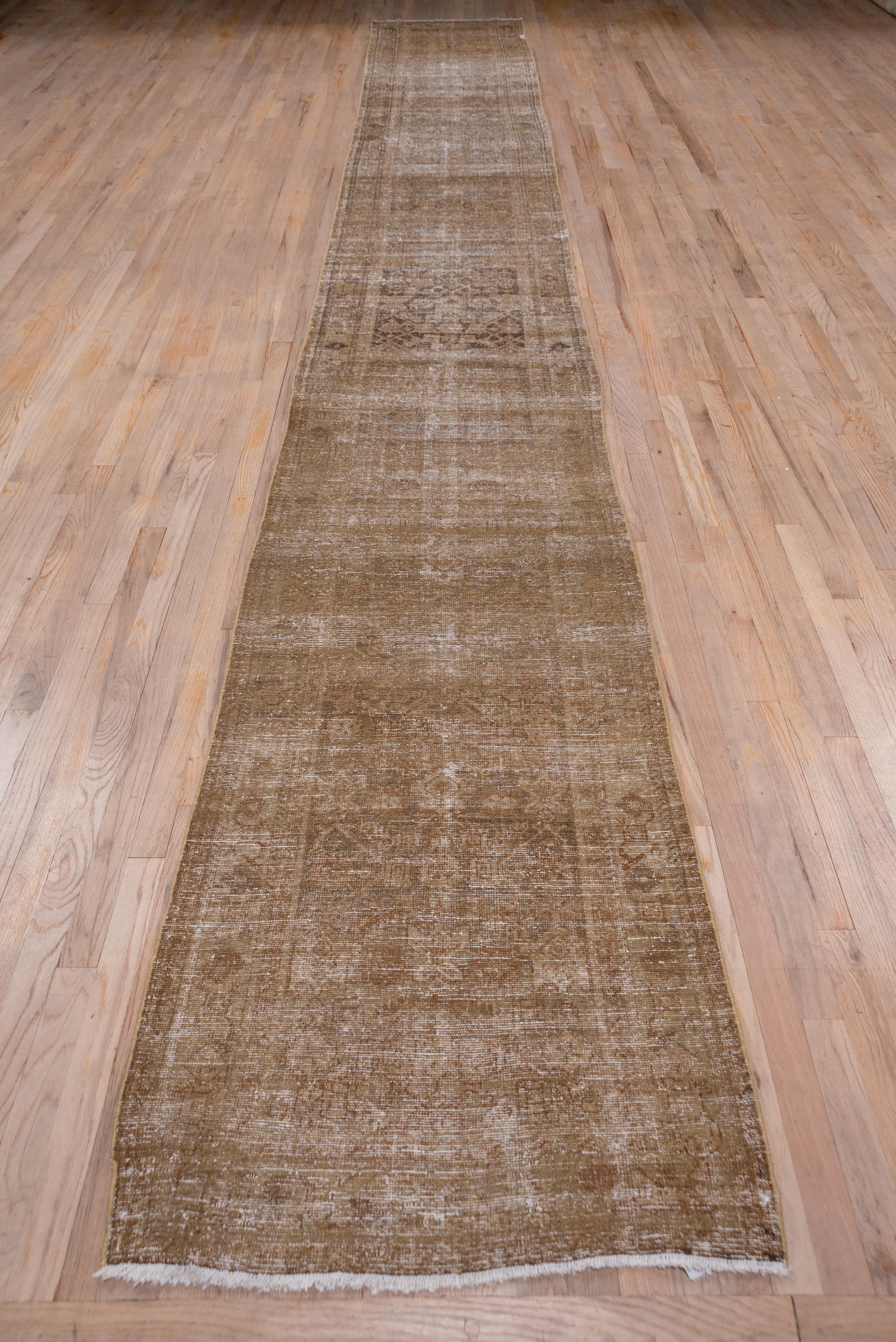 This rather severely all-over worn west Persian village runner shows a bi tonal palette of light and medium warm brown in a typical Herati pattern. The field abrashes to a darker brown near the centre.