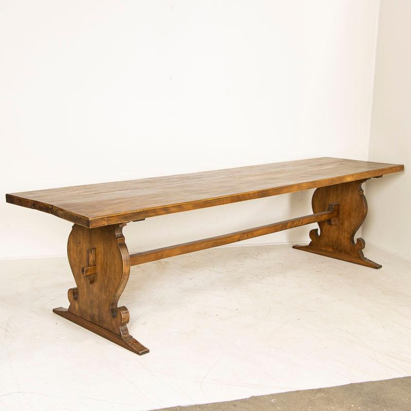 Strong and substantial, this long narrow farm table will invite the entire family to sit and linger. Notice the sturdy trestle base holding the large top made from 3 long planks at just under 10' long. This style of trestle base easily allows chairs
