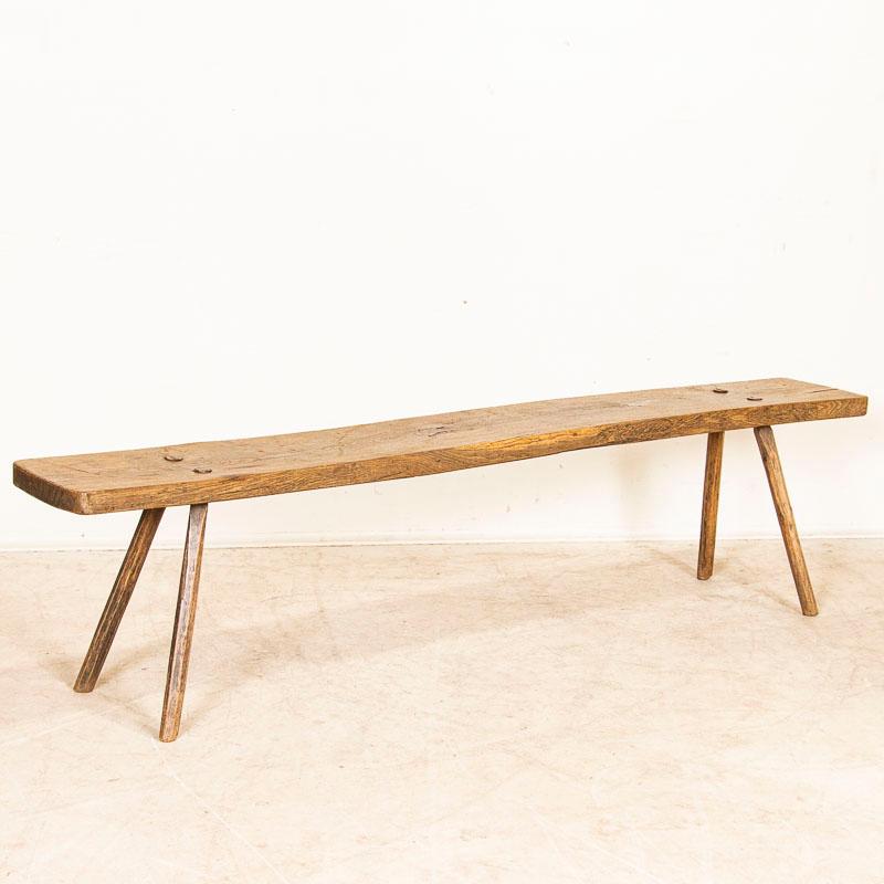 Delightful in simplicity, this old bench is reminiscent of a simpler time. Note the peg splay legs, aged distress with old cracks, gouges, scratches and wear seen in the bench seat, all adding to its European country charm. This 6.5