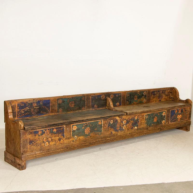This long antique pine bench from Romania still maintains the original painted finish and is dated 1888. The traditional Folk Art of the late 1800's in Eastern Europe included floral motifs painted in panels, often using blue or red backgrounds such