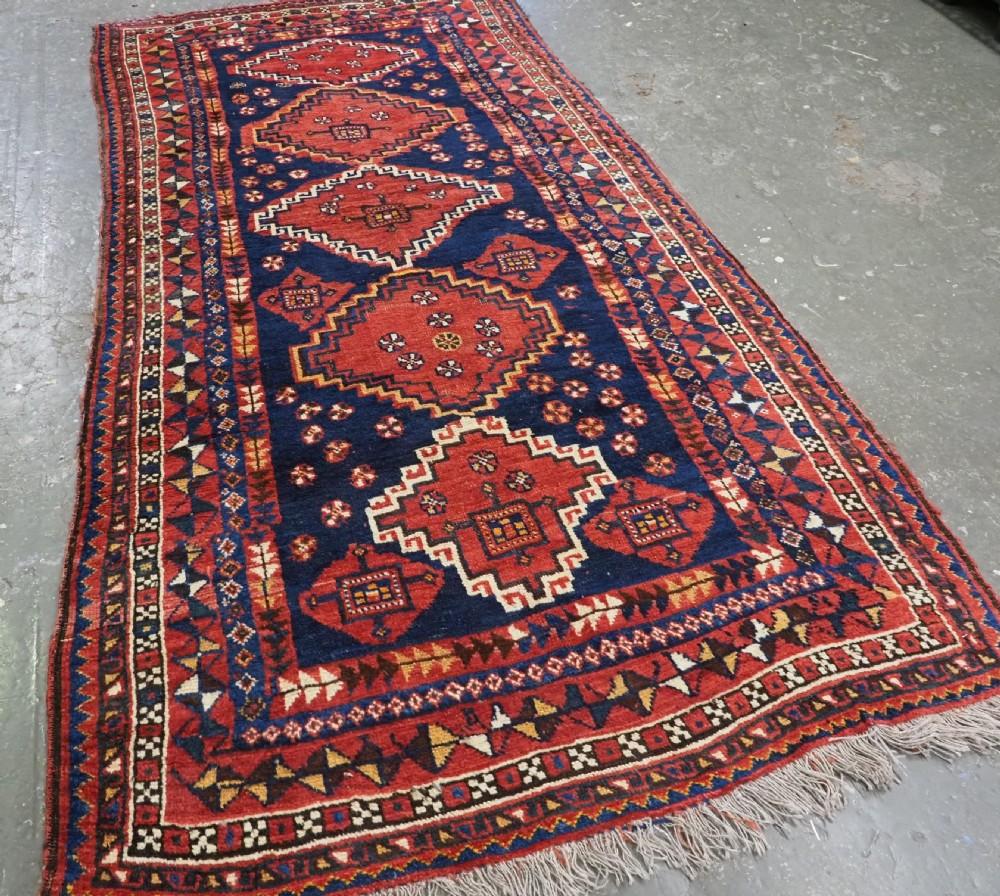 Antiker langer Luri-Stammesteppich mit Medaillon-Muster
CIRCA 1900

Dieser Teppich ist ein exzellentes Beispiel für die Luri-Stammesweberei, mit einem Feld aus fünf Riegelhakenmedaillons Die Medaillons sind mit Rosetten und anderen Stammesmotiven