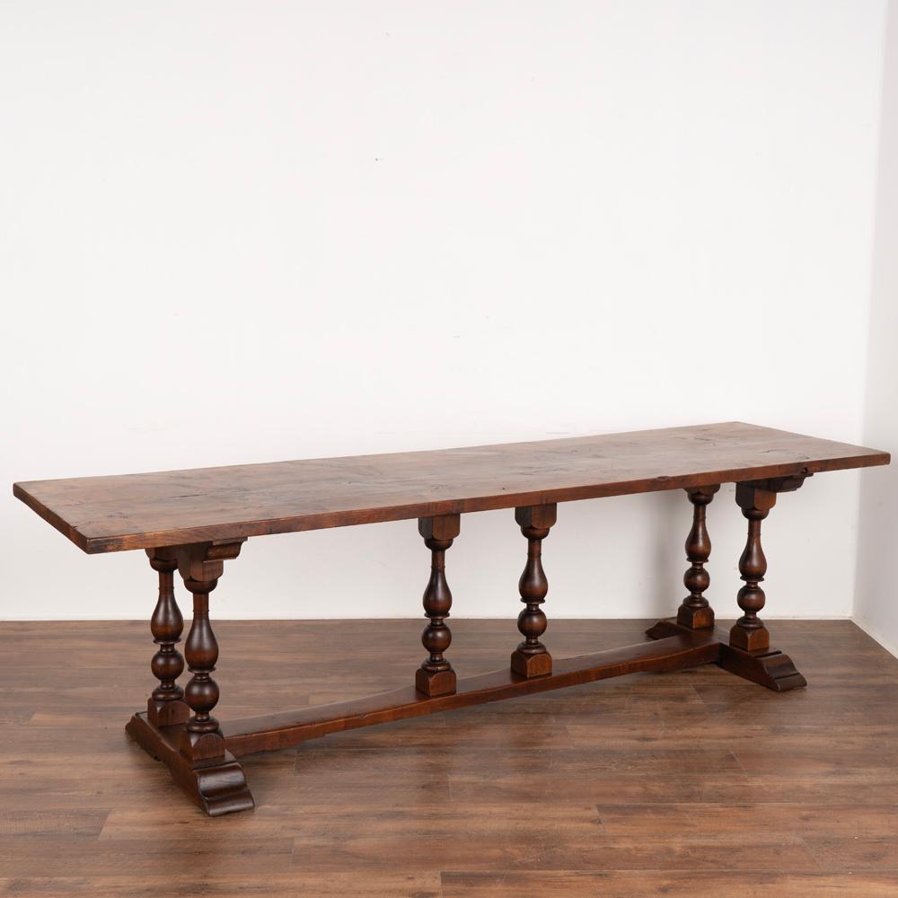 The stunning walnut wood is the highlight of this long refectory or library table from France.
The balance of six turned legs and long stretcher make it easy to accommodate chairs for a dining table. 
The top is comprised of 4 planks of oak, which