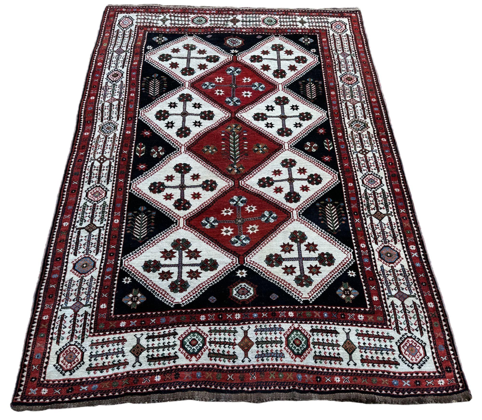 Un meraviglioso tappeto tribale antico, tessuto a mano dalla tribù nomade dei Lors intorno al 1920. Il design presenta un'audace grafica di fiori stilizzati circondati da un bordo avorio. È insolito trovare una tessitura tribale in queste
