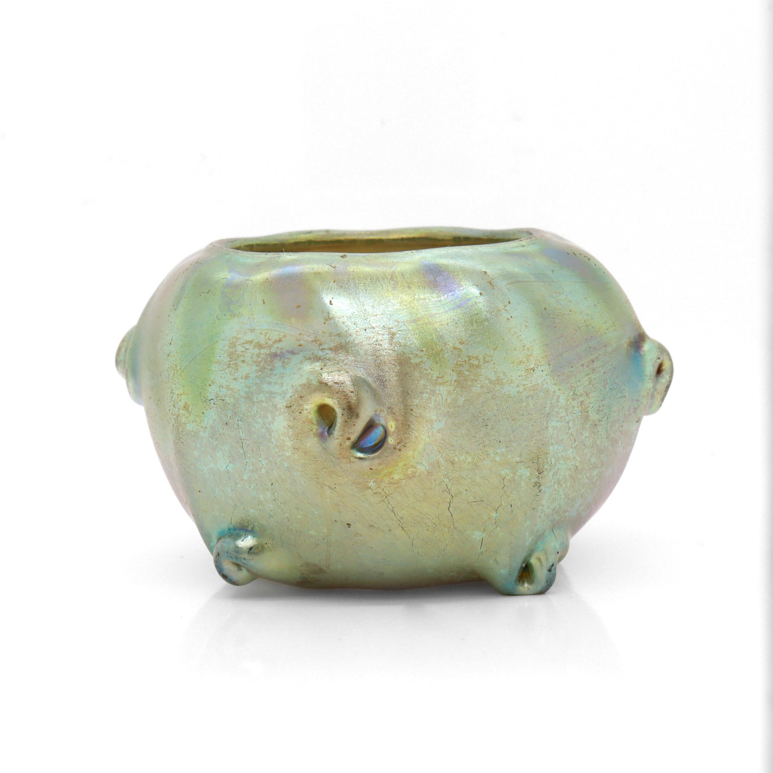 A fine antique art glass miniature vase or salt cellar.

By Tiffany.

Of a petite squat form with serpentine nodes and a greenish gold iridescent finish.

Marked L.C.T. to the foot.

Simply a piece of Tiffany Favrile art glass!

Date:
20th