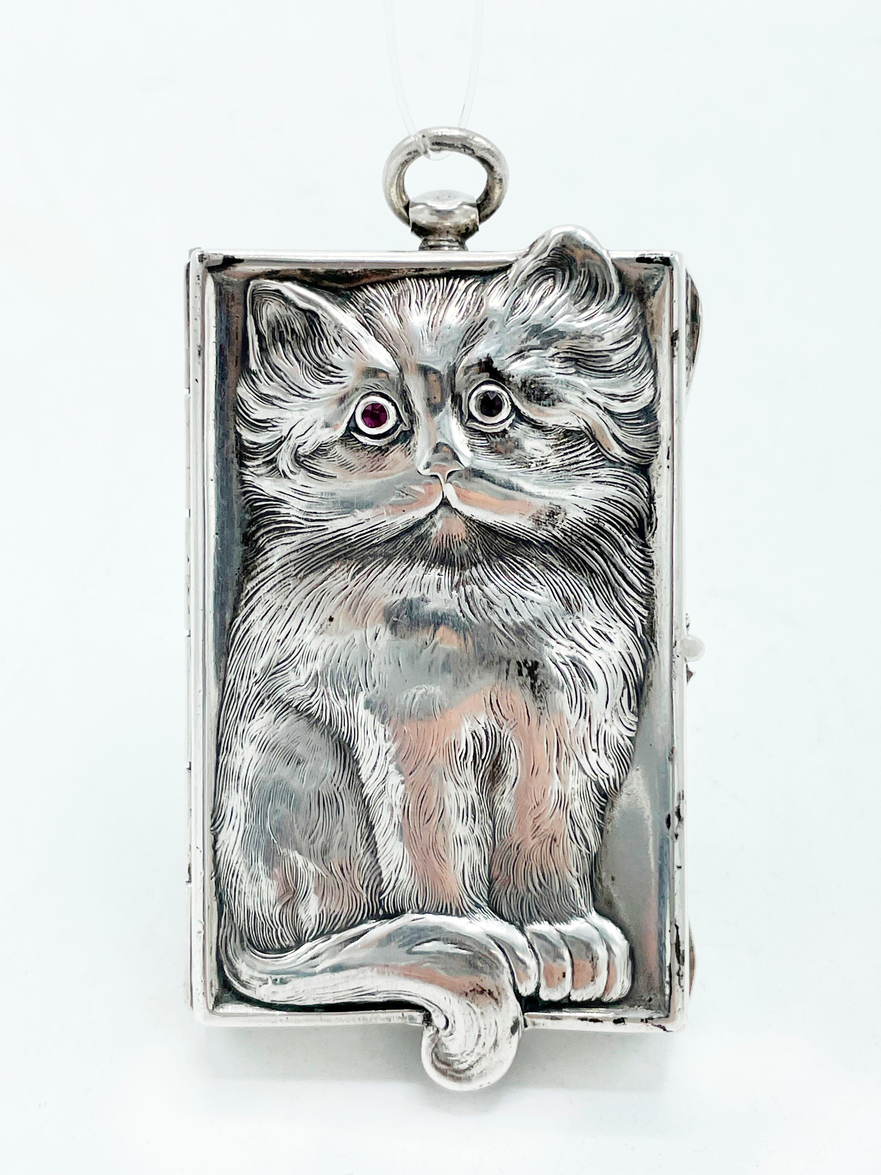 A magnificent antique German solid silver Minaudière adorned with a silver cat engraved in deep relief on the front of the case, with the back of the cat on the back cover. The cat is encrusted with precious jewels with ruby ​​eyes.
The interior has
