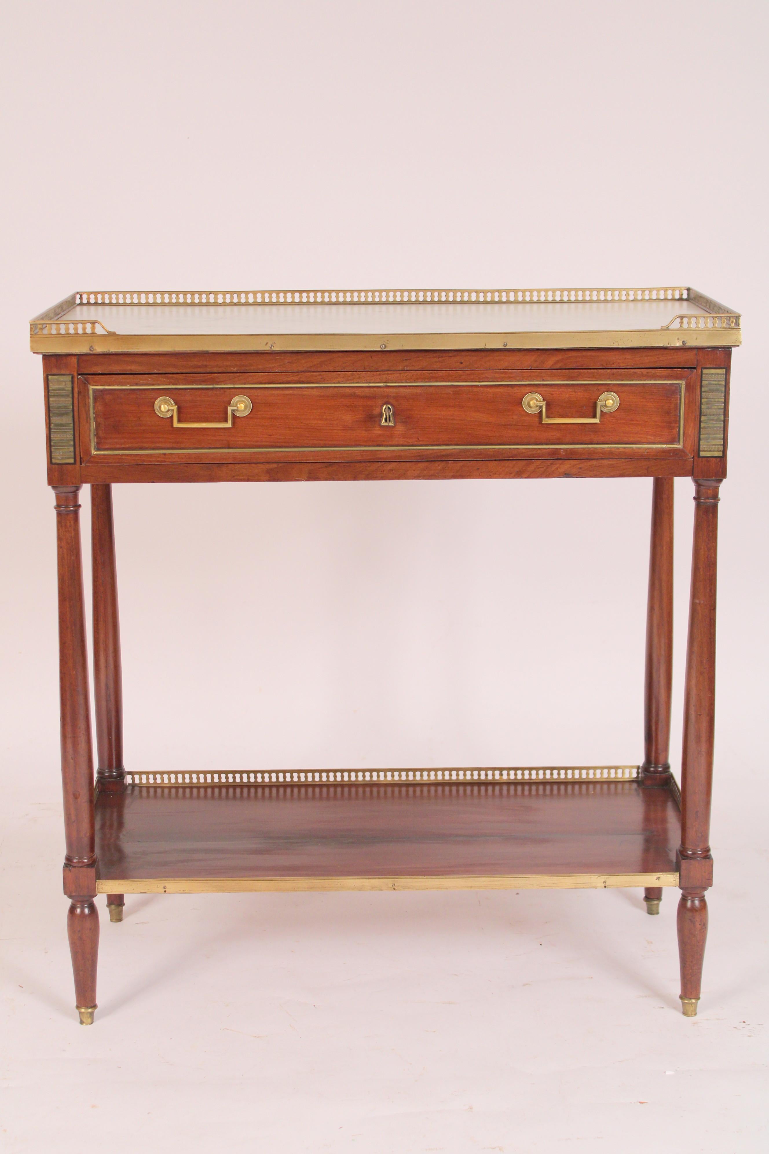 Antique Louis XVI style mahogany console desserte with marble top, 19th century. The carrera marble top with a reticulated brass gallery, a frieze drawer with brass molding and old brass hardware, turned supports between frieze drawer and lower