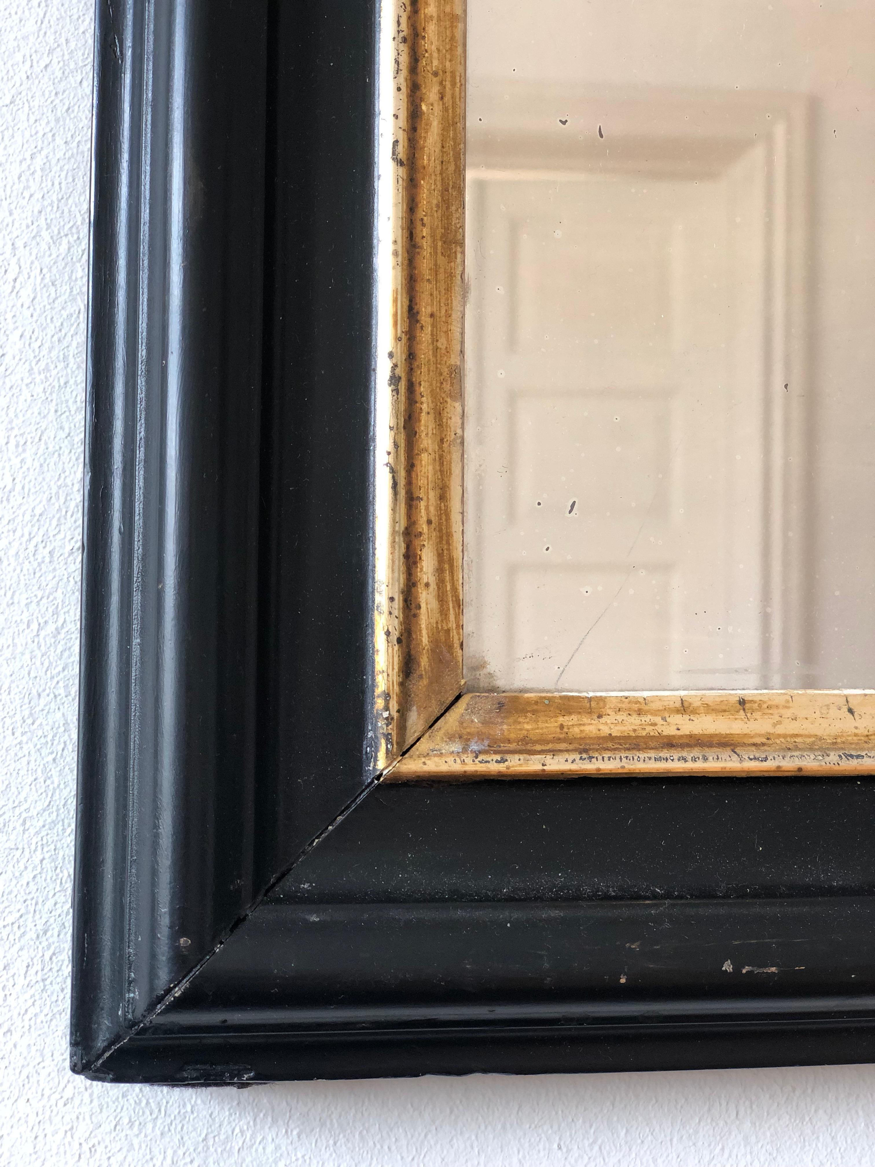 An enchanting antique Louis Philippe French mirror, dating to the late 19th century. The small full length mirror features a refined black frame with a soft gold trim and a gracefully curved top, exuding timeless elegance and charm.

Object:
