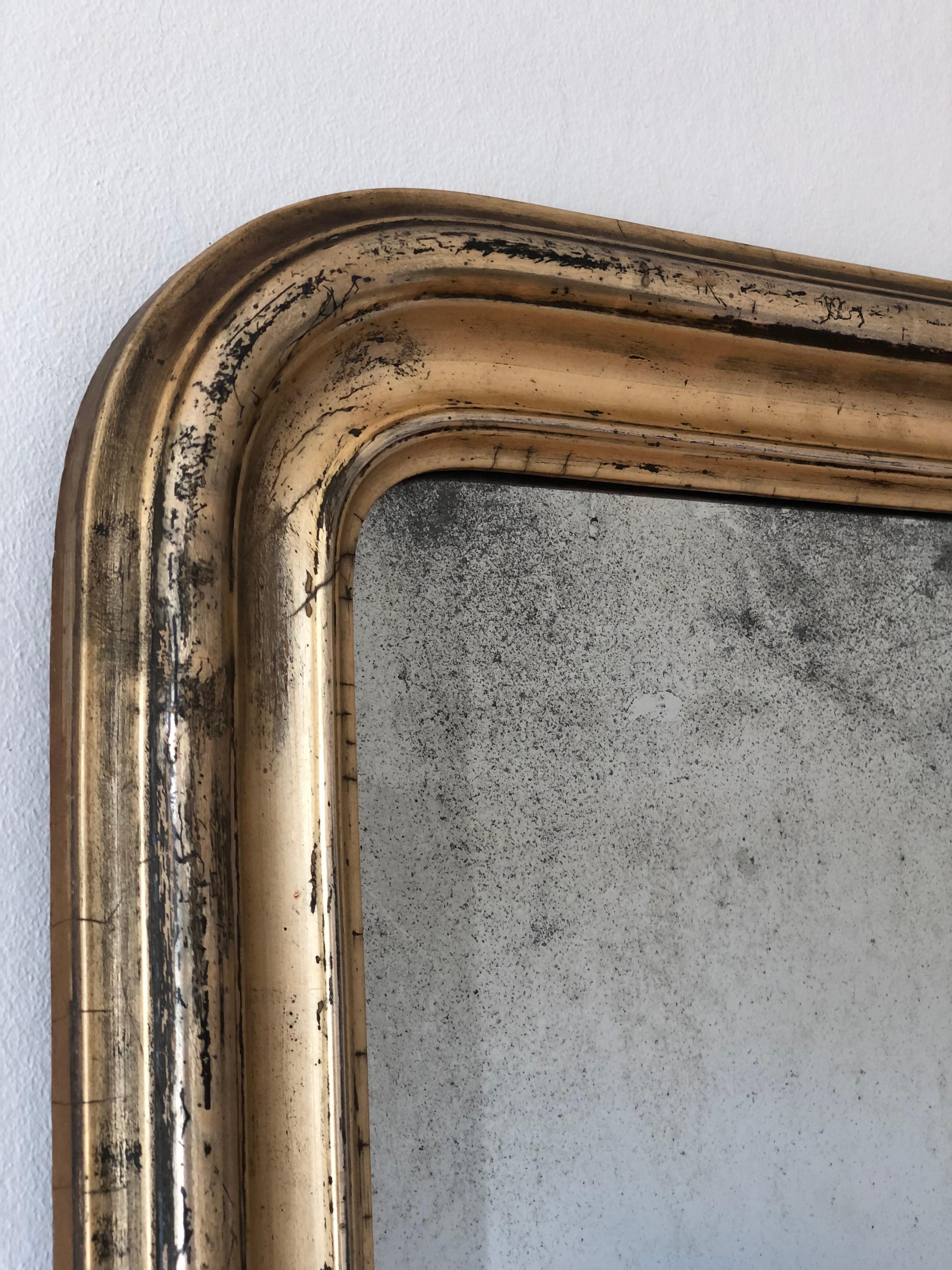 An antique Louis Philippe small full length mirror from France, dating to the late 19th century.
With an appearance of grandeur, the richly carved giltwood frame features gracefully curved top corners and has a beautiful worn gold leaf patina. The