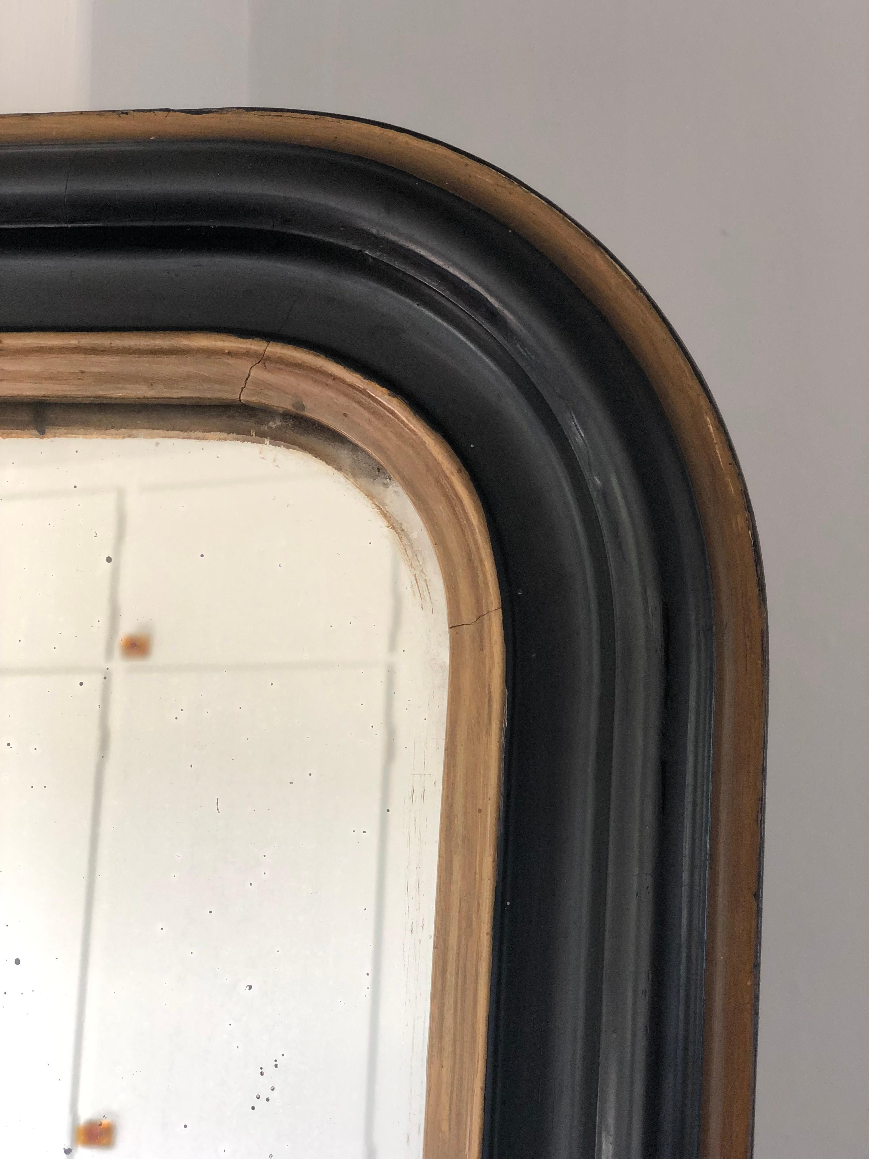 19th Century small but heavy giltwood full length Louis Philippe mirror in black and gold with curved top corners. Original mercury glass and back.

Beautifully weathered mirror In good condition. France, Late 19th Century.

Object: Mirror
Designer: