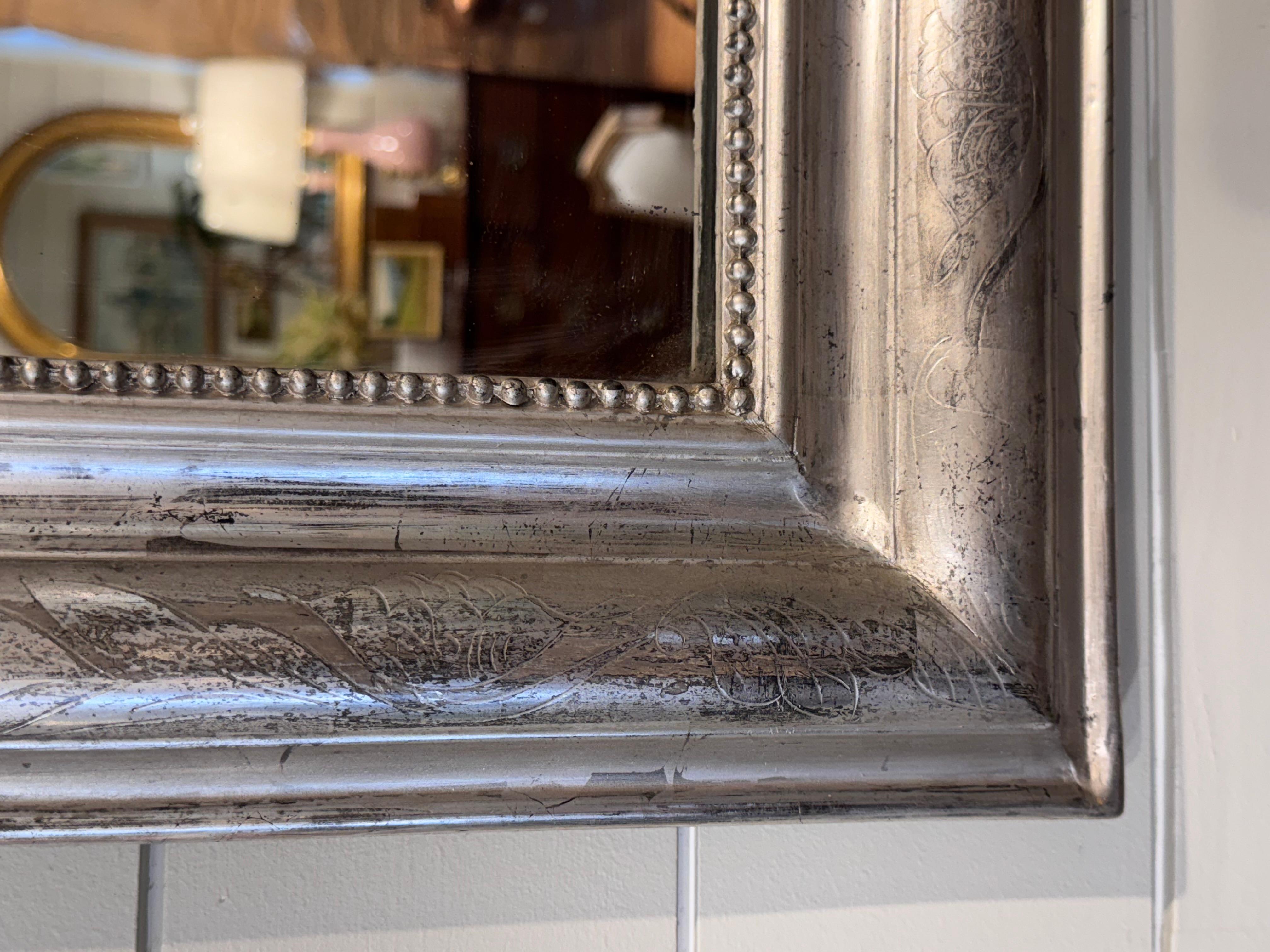 This is a gorgeous 19th century Louis Philippe Mirror! There is hand carved detail on the edges of the mirror in a simple but pretty style. Silver mirrors are harder to come by in this style making finds like this one special. This mirror has aged
