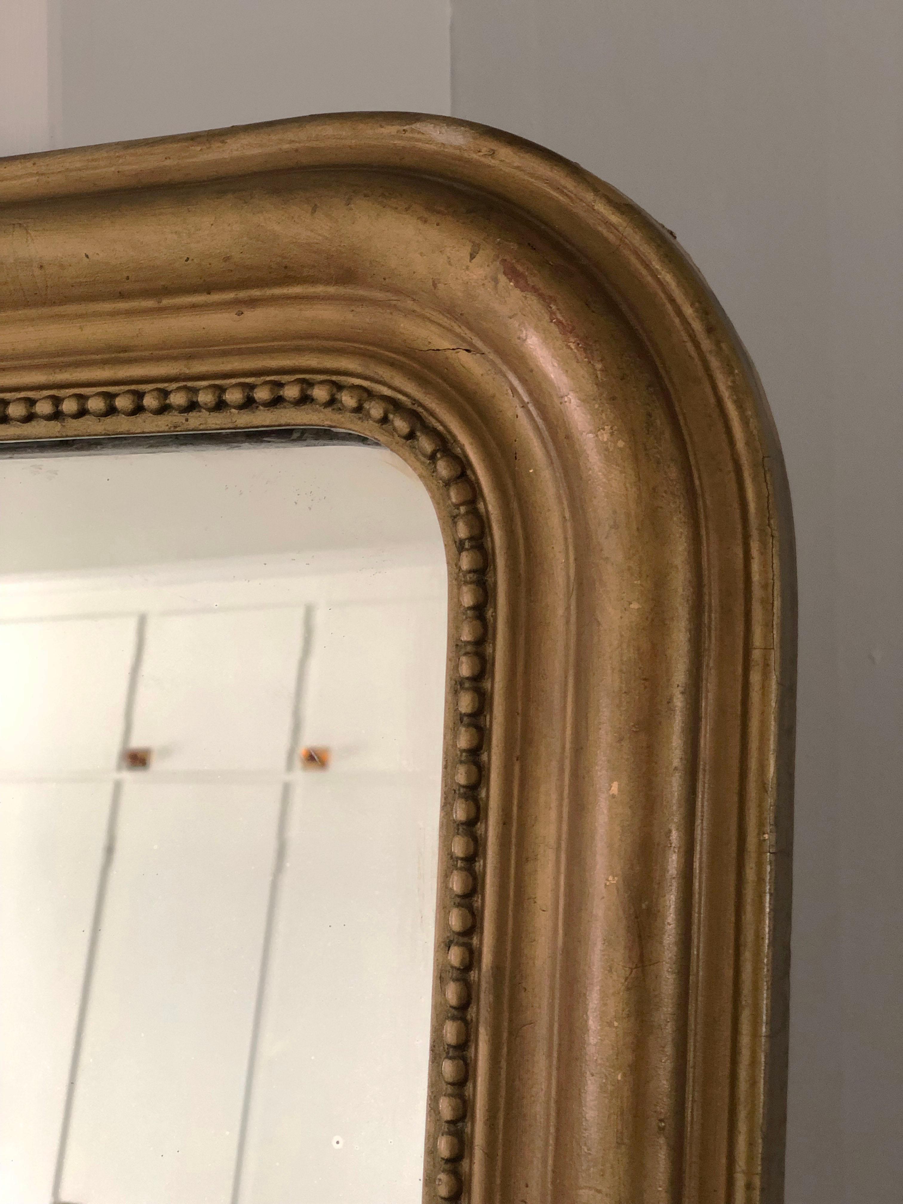 Miroir Louis Philippe ancien du 19ème siècle en bois doré avec une belle patine usée à la feuille d'or. Les coins supérieurs sont incurvés et le cadre est entouré d'une bordure perlée. Verre de mercure et dos d'origine.

Miroir magnifiquement patiné