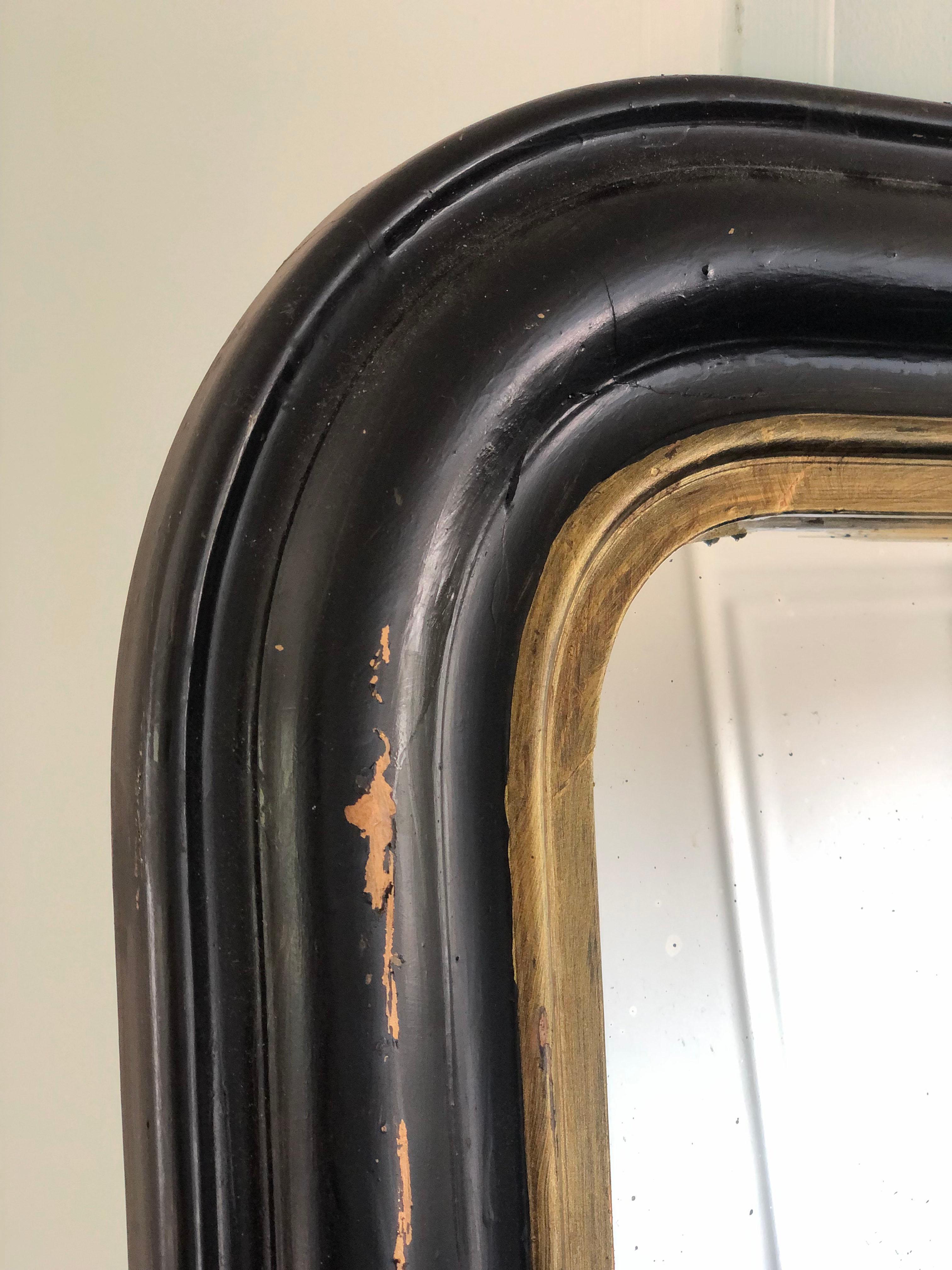 19th Century giltwood Louis Philippe mirror in black and gold with curved top corners. 
Beautifully weathered mirror In good condition. France, Late 19th Century.

Object: Mirror
Designer: Unknown
Style: Antique, Louis Philippe
Period: