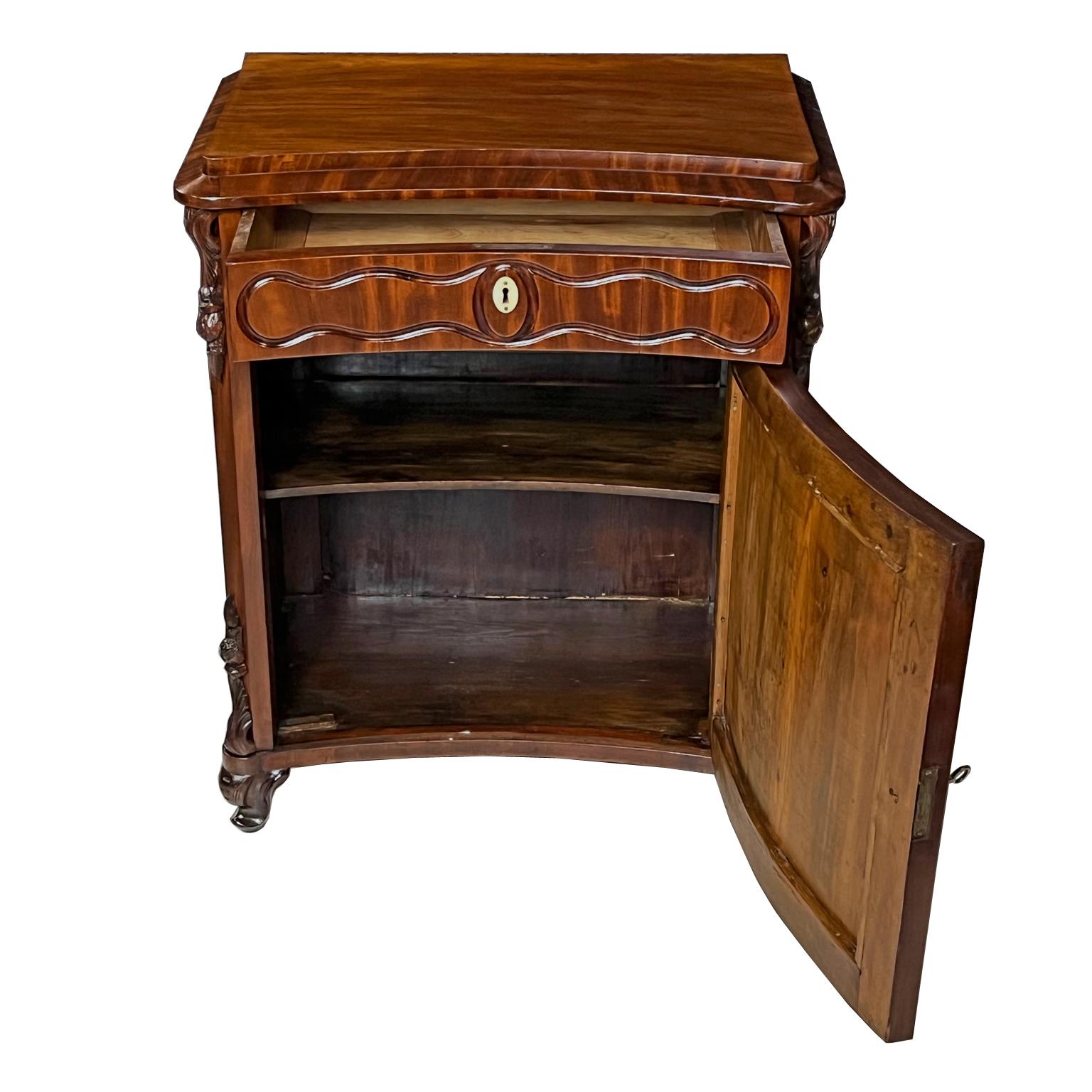 A very lovely Louis Philippe nightstand or side table in fine West Indies/ Cuban mahogany with a concave front. Offers one drawer over a cabinet door that opens to interior shelving. Features a pedestal top with curvilinear inset panels on drawer &