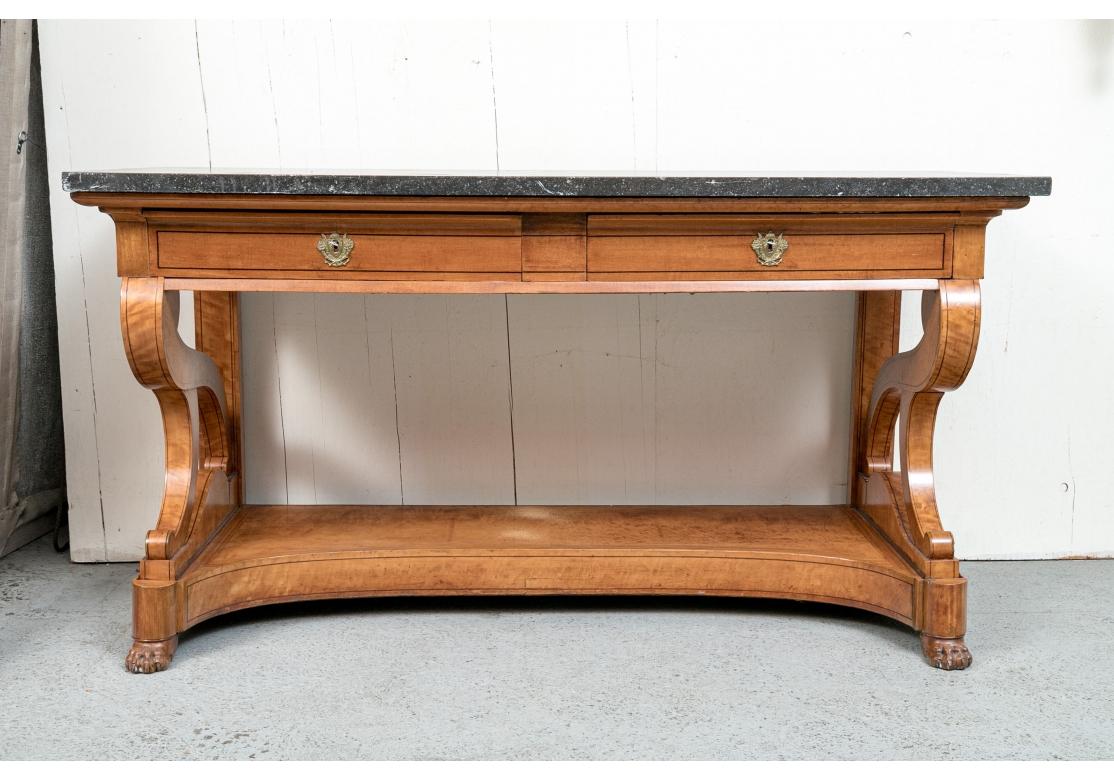 Antique neoclassical console table with black stone top having a moulded frieze, scroll supports, two green lined drawers with brass escutcheons and key pulls, raised upon a plinth base with carved paw feet.

Dimensions: 24 1/2
