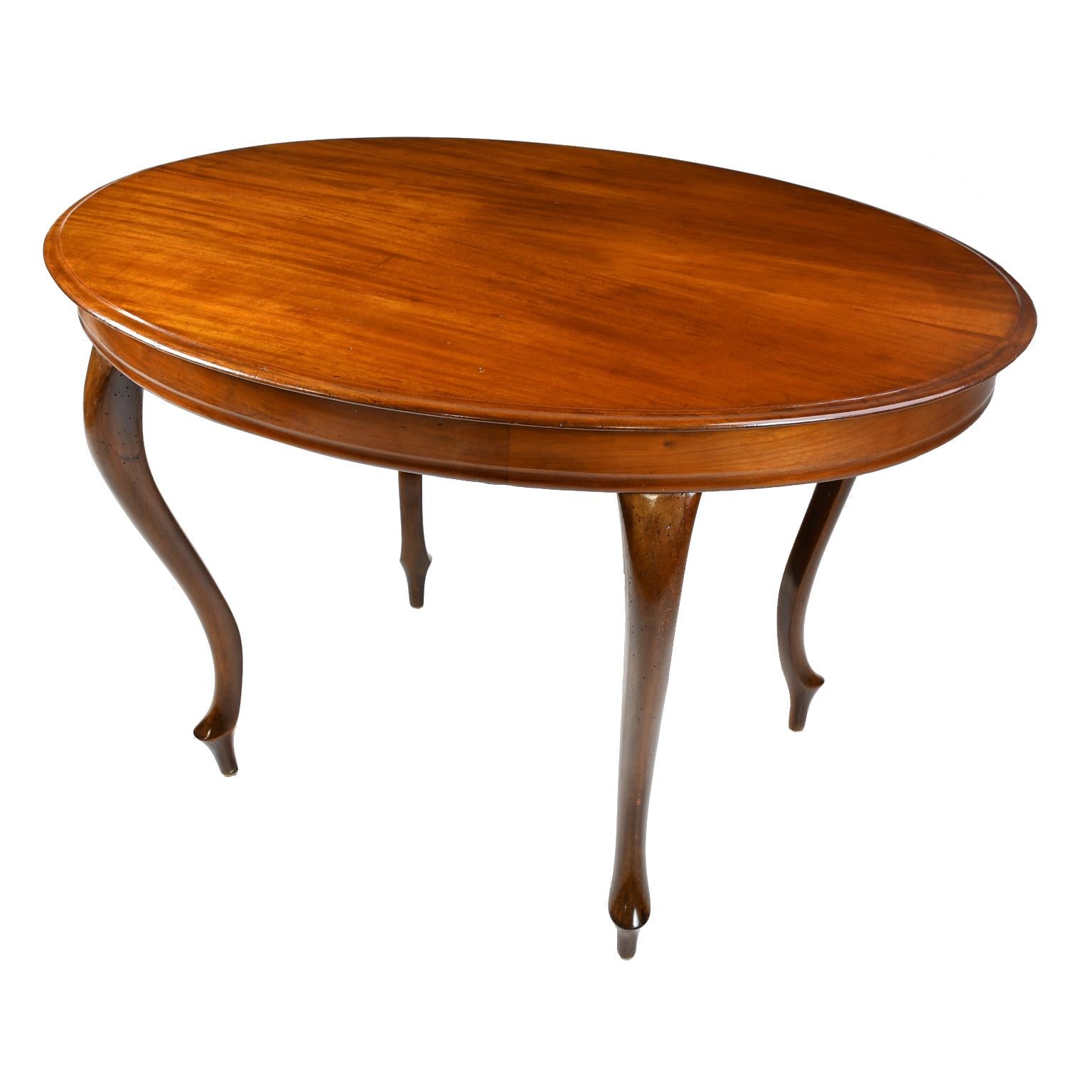 A fine Louis Philippe style salon table with oval top and scalloped apron resting on four graceful, carved cabriole legs. Top is made of beautiful bookmatched, solid mahogany. The apron is banded with a thick face cut mahogany. Legs are made of