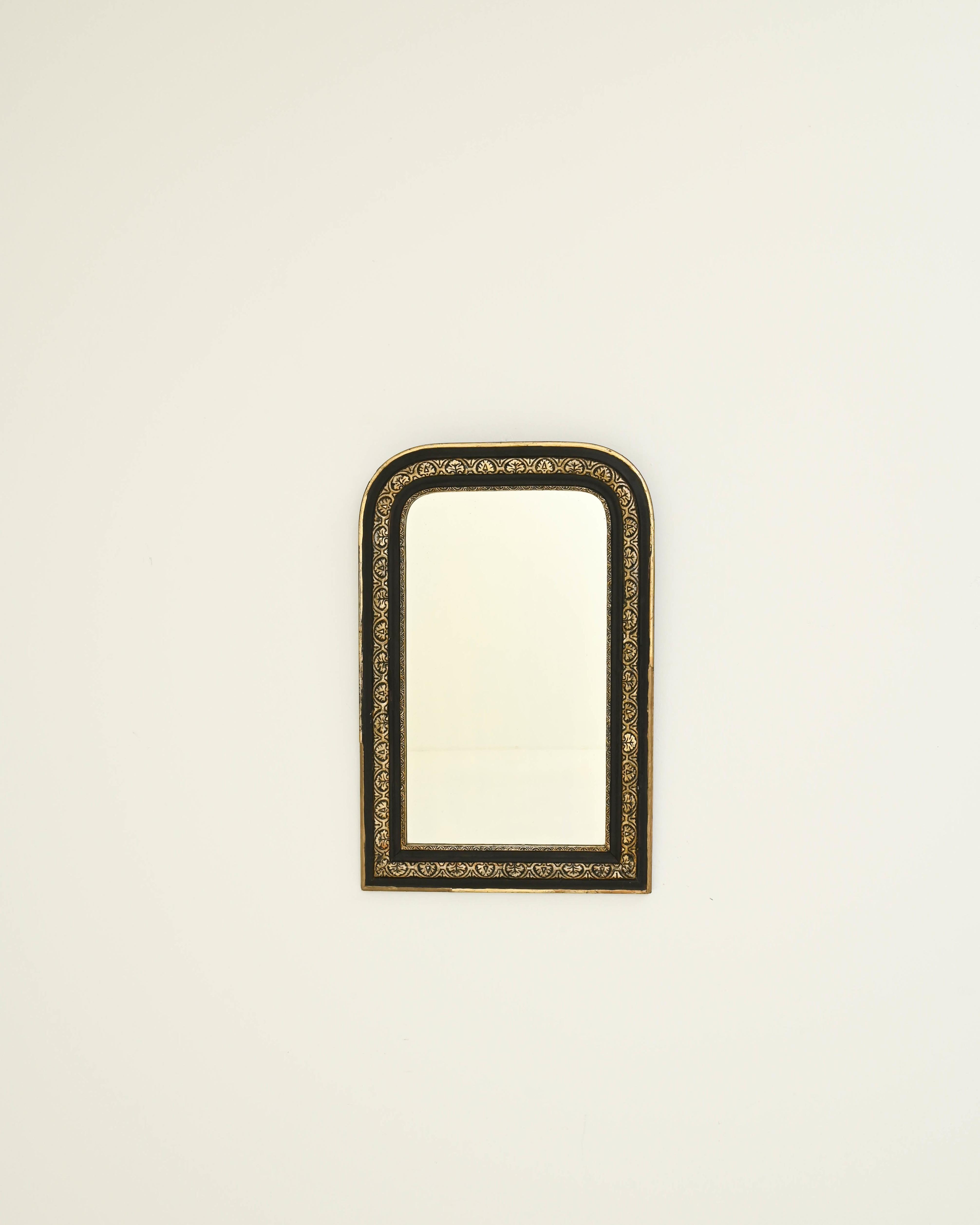 This Louis Philippe mirror was made in 19th-century France. It showcases an elegant black-patinated frame with rounded top corners and squared-off bottom corners, finished in gold leaf that accentuates the foliate pattern artfully carved in the