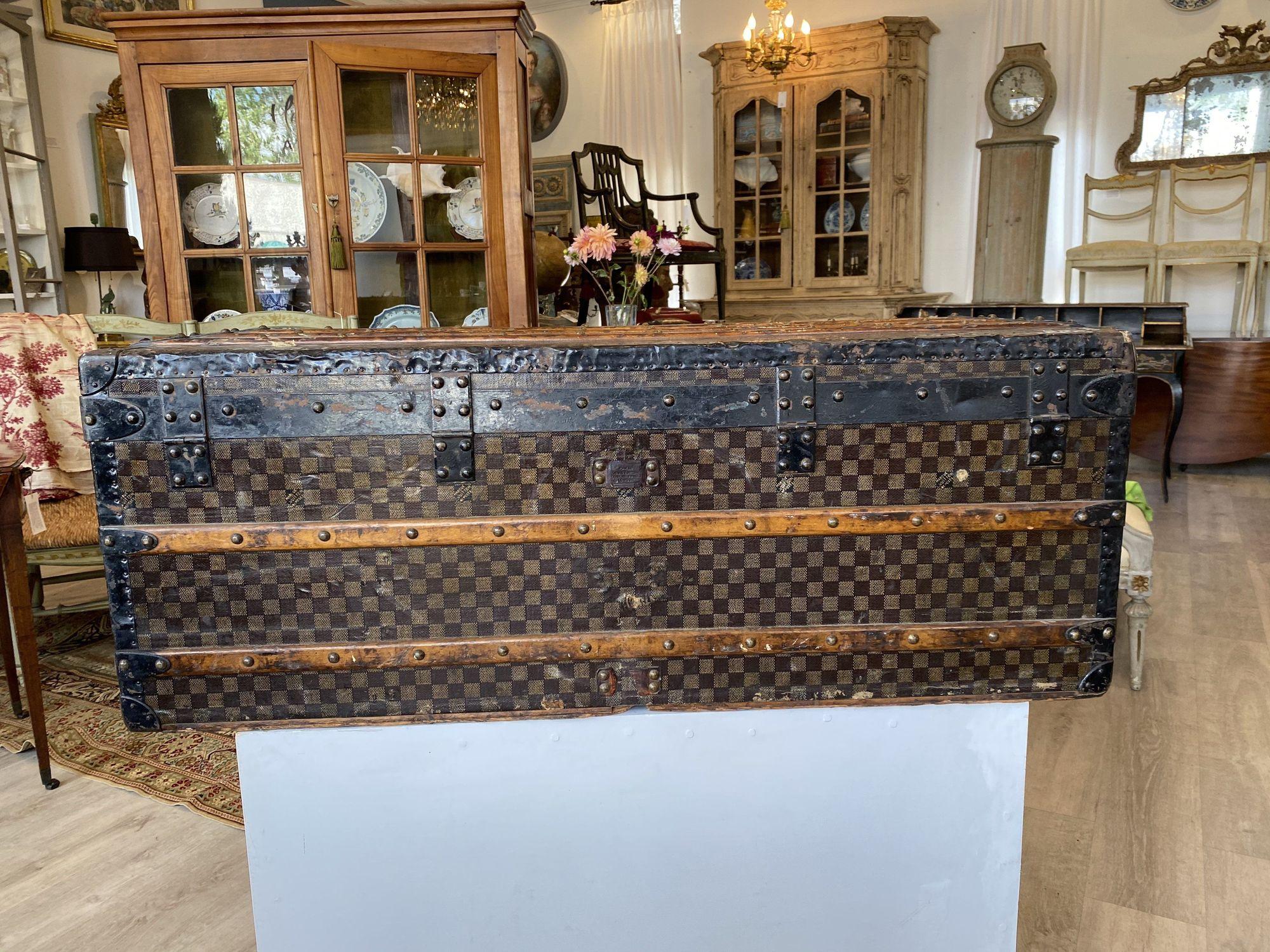 Antique Louis Vuitton Damier pattern trunk, lock plate with Paris rue Scribe Address and London Strand Address; black enameled metal edges, iron handles and bottom, bronze corners, wood slides to long sides and bottom; with 