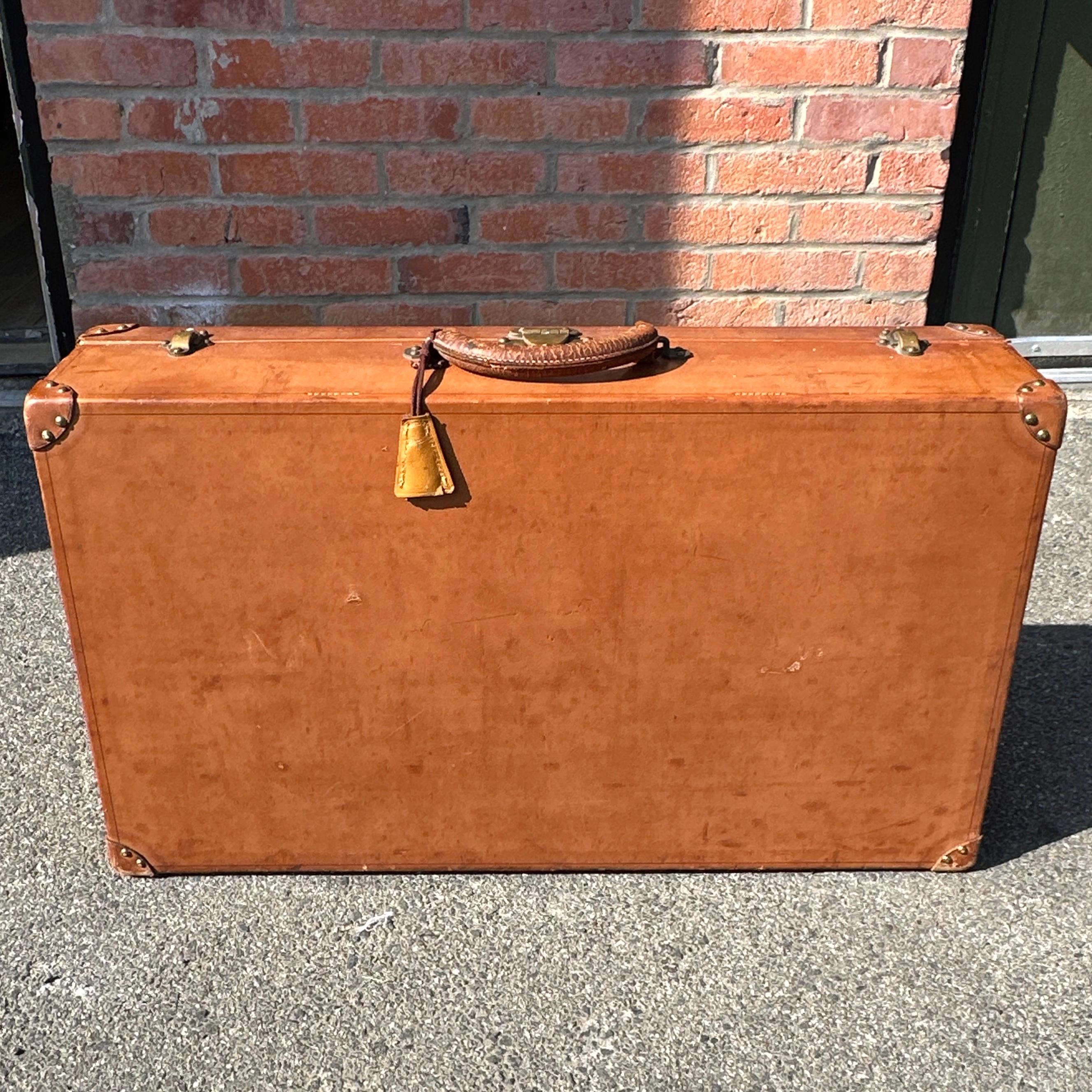 A distinguished piece of travel history, this antique Louis Vuitton hardcase suitcase is a fine example of the craftsmanship that defined luxury travel in the early 20th century. Constructed from richly patinated natural leather, this suitcase