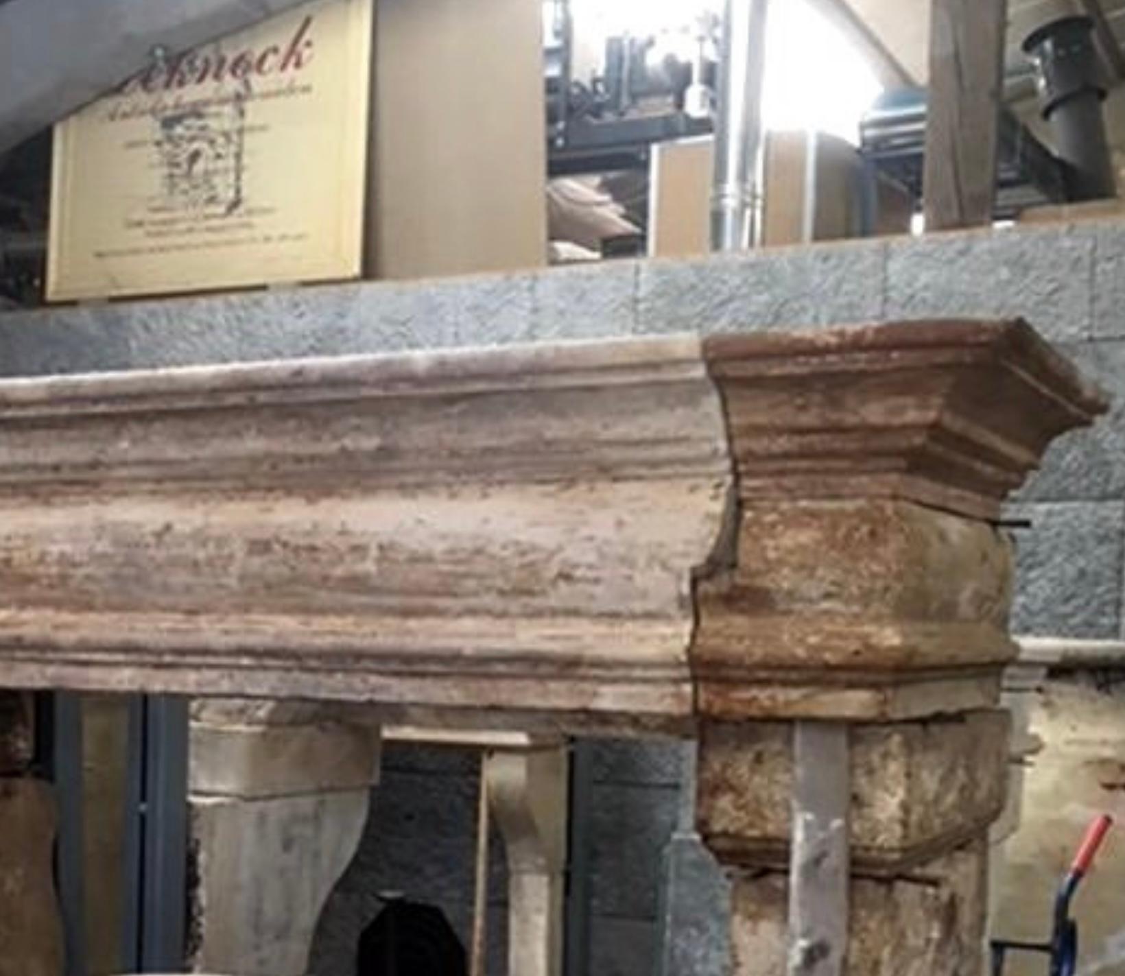A stunning example of an antique French Louis XIII fireplace surround in limestone. The mantle piece exhibits a beautiful combination of molding details spanning across a pair of corbels and legs atop plinths that complement the same soft curve