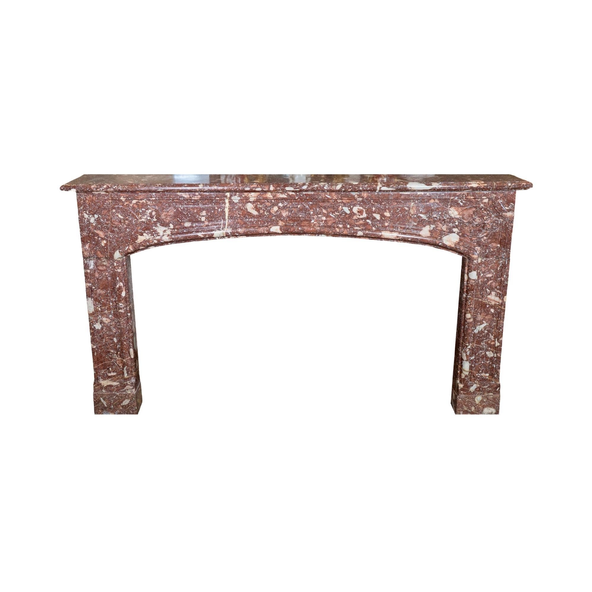Uno splendido caminetto in stile Luigi XIV realizzato in squisito marmo rosso francese. Questo pezzo antico, recuperato e importato dalla Francia, mostra l'eleganza senza tempo del XVIII secolo. La sua bellezza risiede nei sottili ma intricati