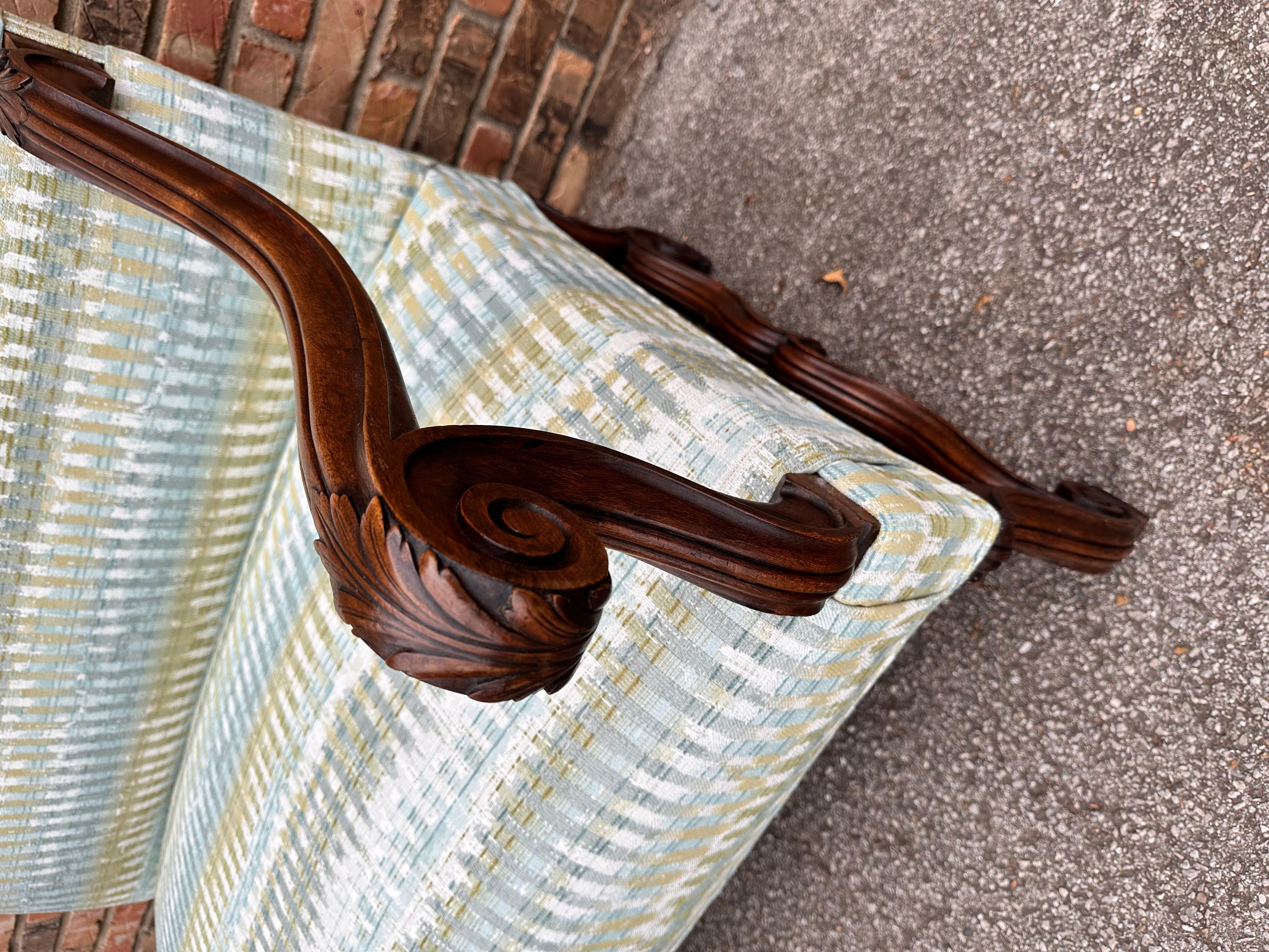 This is an original French antique bench frame that has been newly reupholstered. The new fabric mixes bright yet unobtrusive blue, green, and white tones in a plaid/tweed pattern. The colors pair well with the dark wood of the bench, and the hand