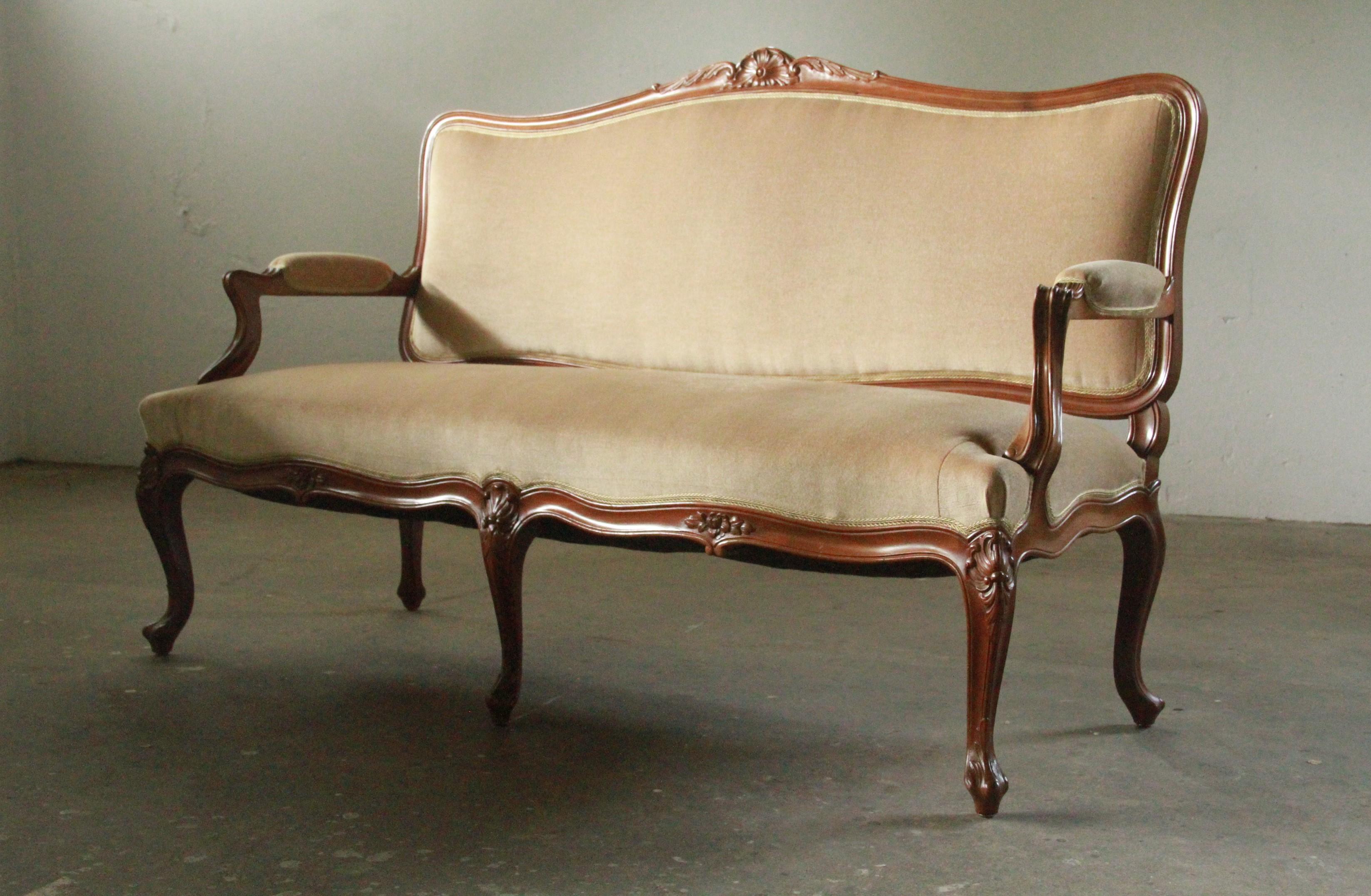 Ce canapé en bois sculpté et décoré à la main, datant du milieu du XVIIIe siècle, incarne l'élégance française intemporelle. Canapé français classique, il présente un dossier incurvé avec des sculptures complexes, des pieds cabriole et un tablier
