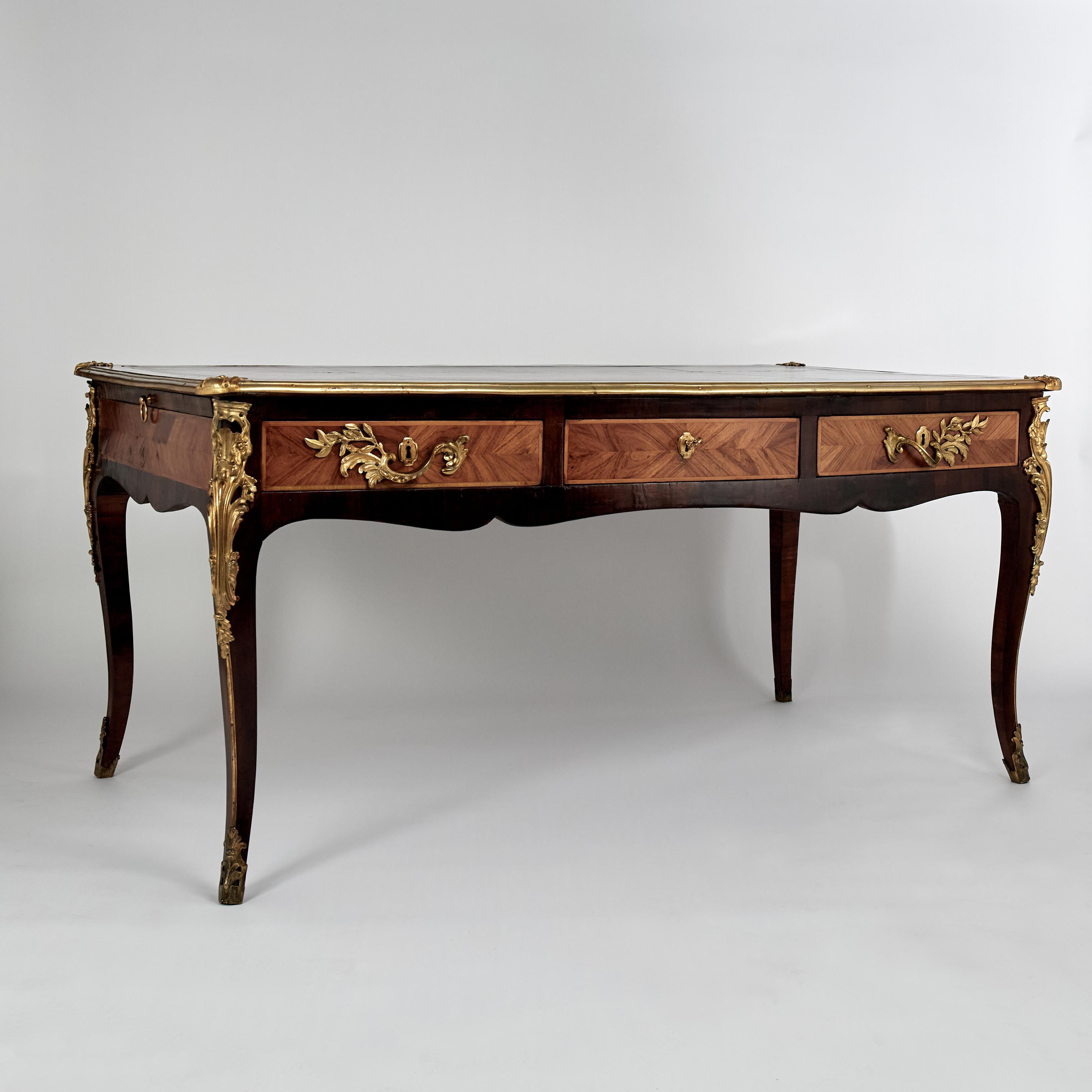 Impressive 18th Century Louis XV bureau plat handcrafted in classic style with mahogany and kingwood, featuring the original tooled oxblood leather top on a brass bound case with three drawers in the front, faux drawers on the reverse and pullout