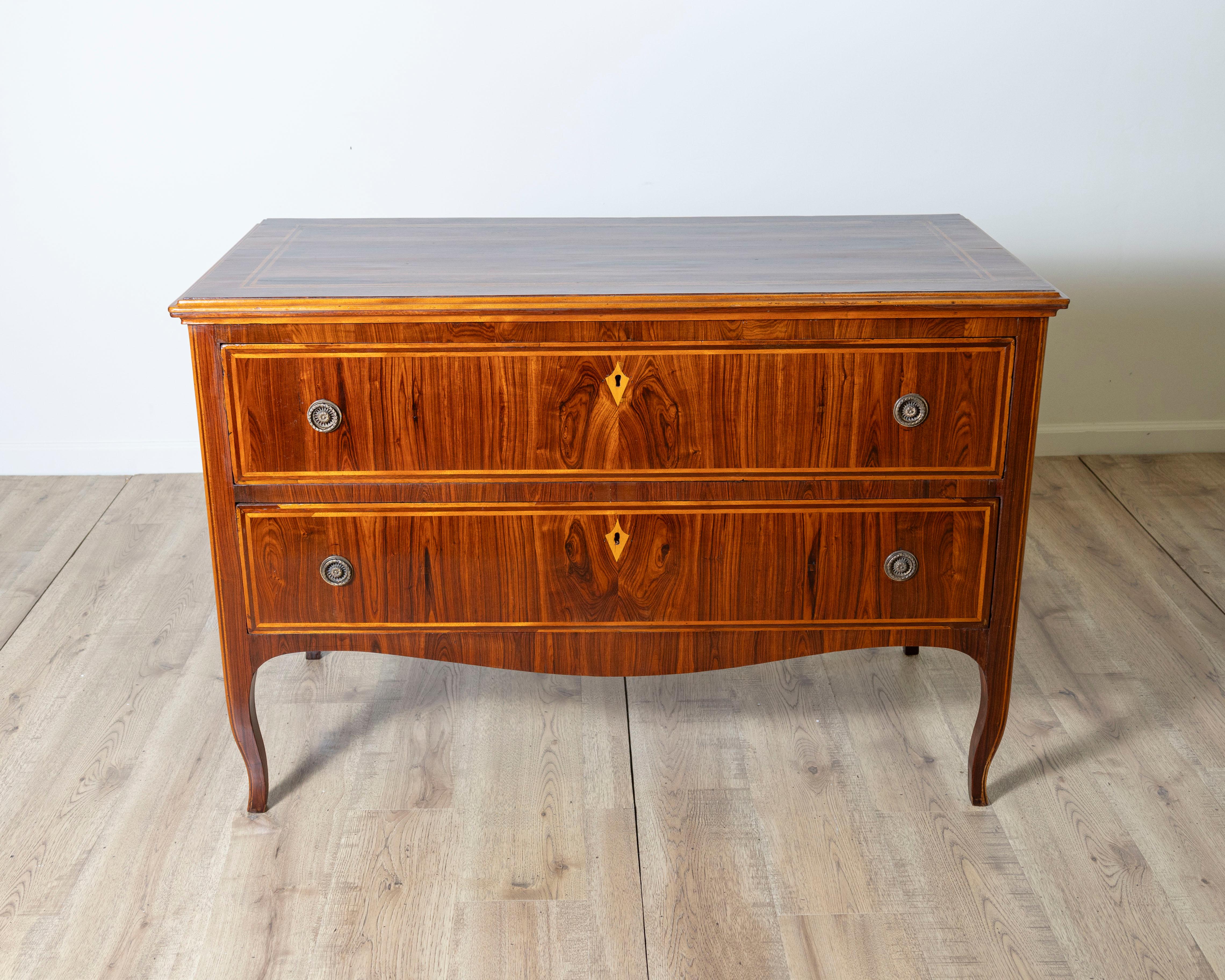 An exquisite 18th century Louis XV commode from the Veneto region, crafted in richly figured palissandre (rosewood) with fine marquetry inlays. This elegant two-drawer chest features a subtly curved apron and gently cabriole legs, characteristic of
