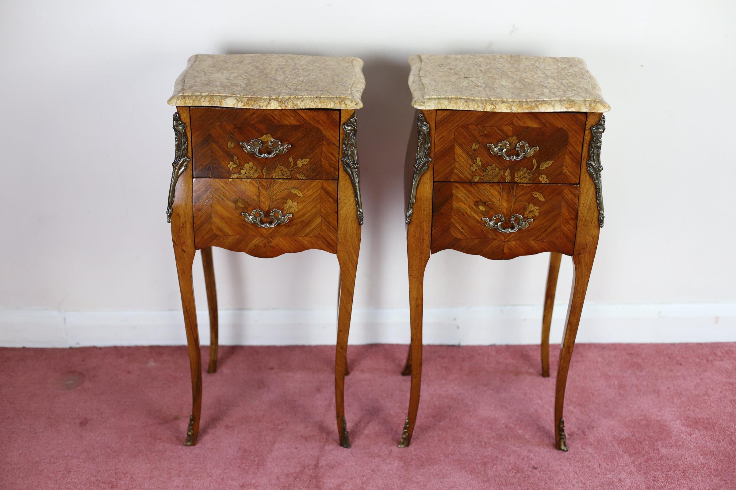 Antique Louis XV French Marquetry Marble Nightstands.
Beautiful pair of tulipwood night antique tables, having serpentine marble tops above 2 flower inlaid drawers fitted with original brass handles and flanked by ormolu decoration, all standing on