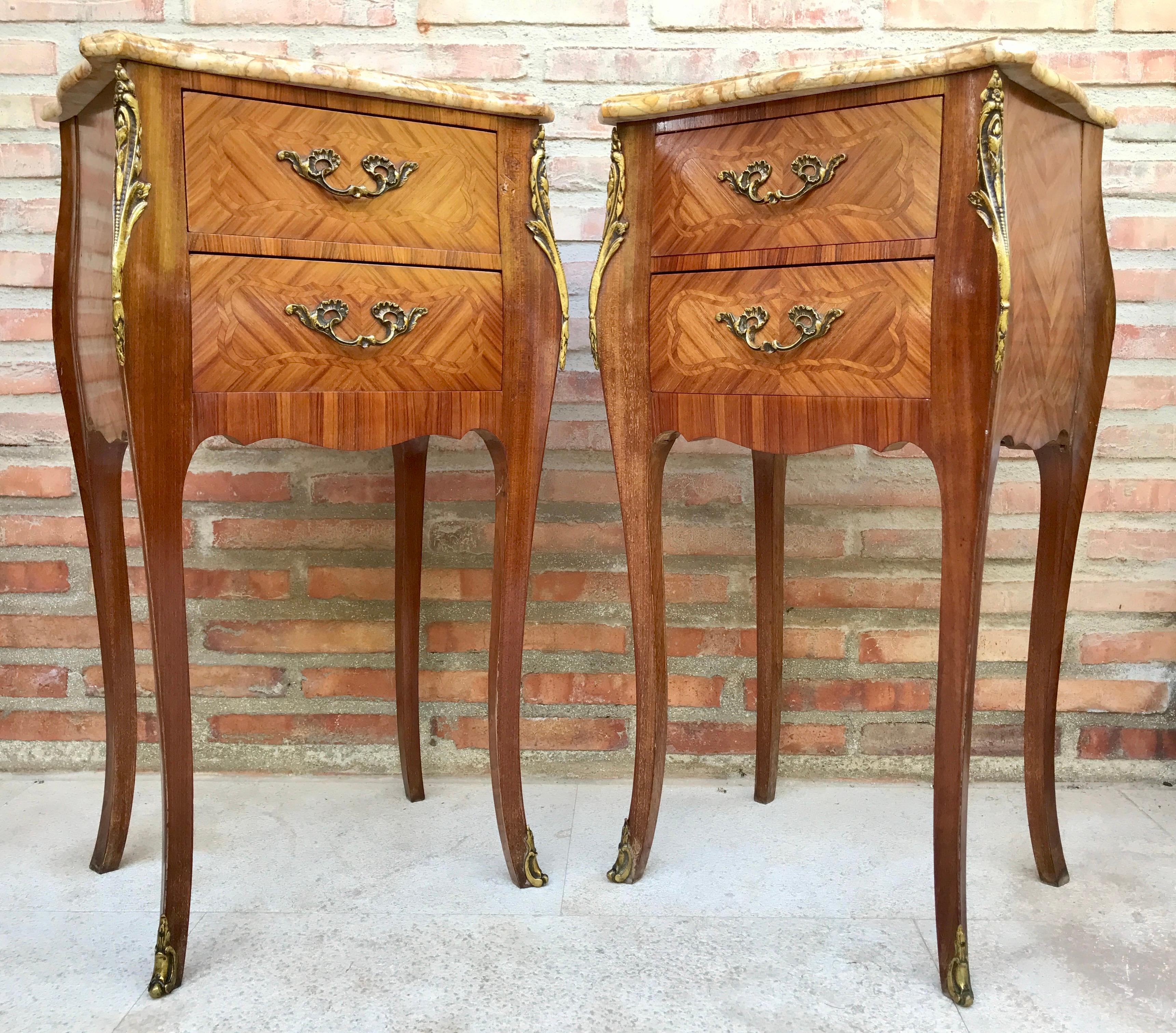 A pair of Antique French Louis XV Marquetry marble top nightstands. Subtle contours and scroll shapes are evident in the corner posts and legs, which support serpentine sides and an arched front façade for a curvaceous effect. The tops are luxurious