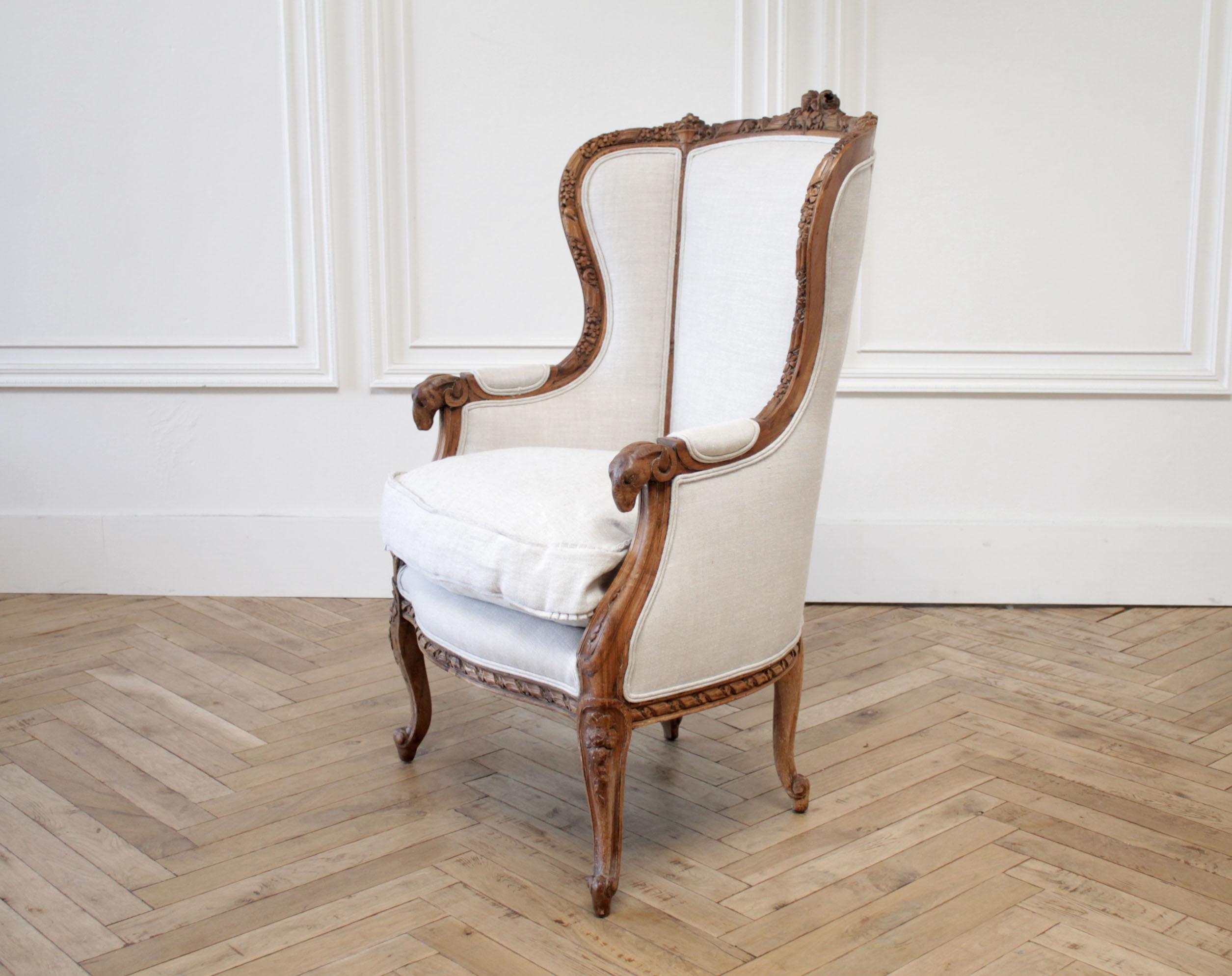 Antique Louis XV style carved wing chair upholstered in natural linen
Carved with large roses and ribbon detailing, a Classic curved leg, and ram's head details at the front of the arms. Natural distressed wood patina, we upholstered this in a