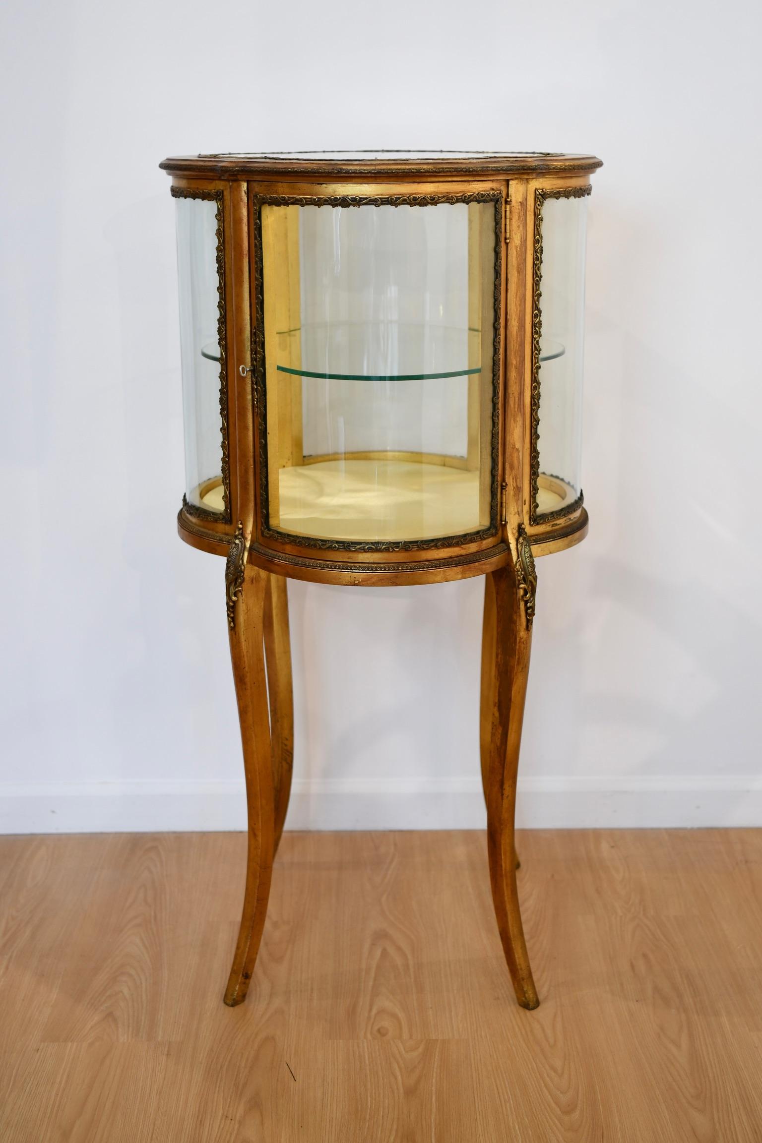 Antique Louis XV style gilt curio vitrine with crown glass on all sides. Includes key however lock does not appear to be functional. Dimensions: 34.25